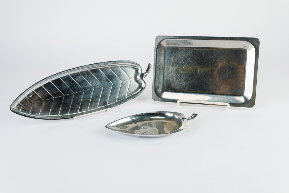 Set of 3 Vintage Metal Serving Trays: Dated vintage, this of three metal serving trays showcases a mix of geometric and organic designs. Two platters are sculpted into elegant leaf forms complete with detailed vein patterns and stylized s