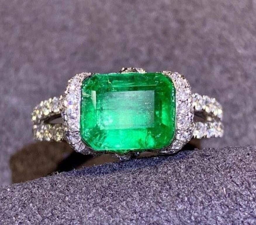 2.2ct Natural Emerald 18Kt Gold Ring: An eye-catching emerald and diamond cluster ring. 18Kt gold deluxe set with 2.2ct natural emerald and 0.89cts natural South African diamonds, The central emerald has an enchanting Vivid green colour,