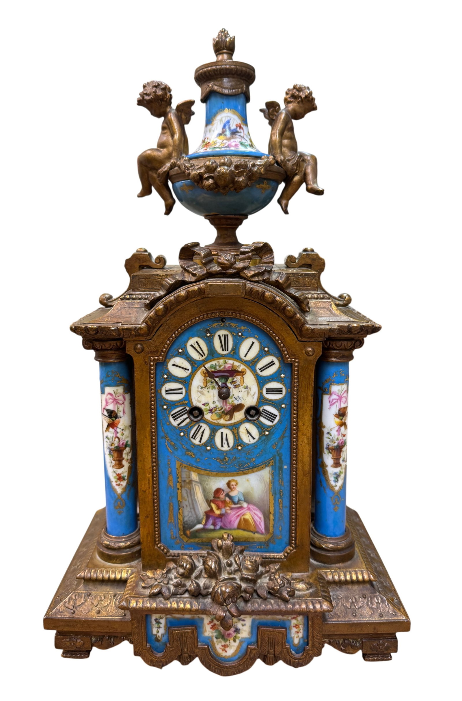 French Neoclassical Sevres Style Mantel Clock: c 1880 Neoclassical mantle clock; bronze with hand-painted Sevres style cartouches with cupid-enhanced urn. Condition: No key, missing hand and not guaranteed working. Dimensions 17" x 9.5" x 5.5."