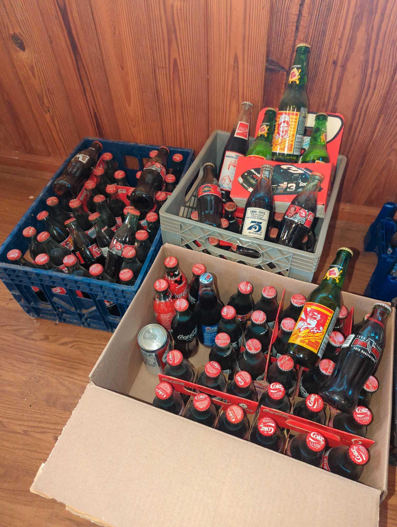 Large Grouping of Coca Cola Bottles: Most are unopened and full of cola. NASCAR designs on some.