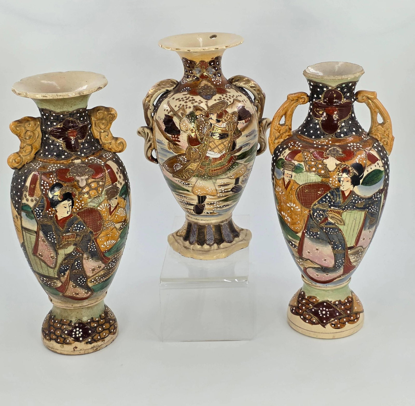 Three Japanese Satsuma Vases, possibly Meiji period, INV. 1079: Comprising Samurai, Geisha and Floral designs. Approx. 11 1/4" height tallest vase. With two holes to top of Samurai vase, with holes to bottom of both Geisha vases, one with broken rim.