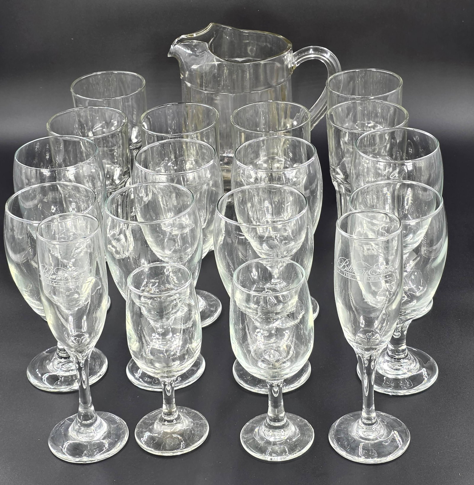 19 Assorted Glassware Items, INV. 1050: Including pitcher, beer mugs, wine glasses and champagne glasses. 7 3/4" height of pitcher. 7" height?of wine glass.
