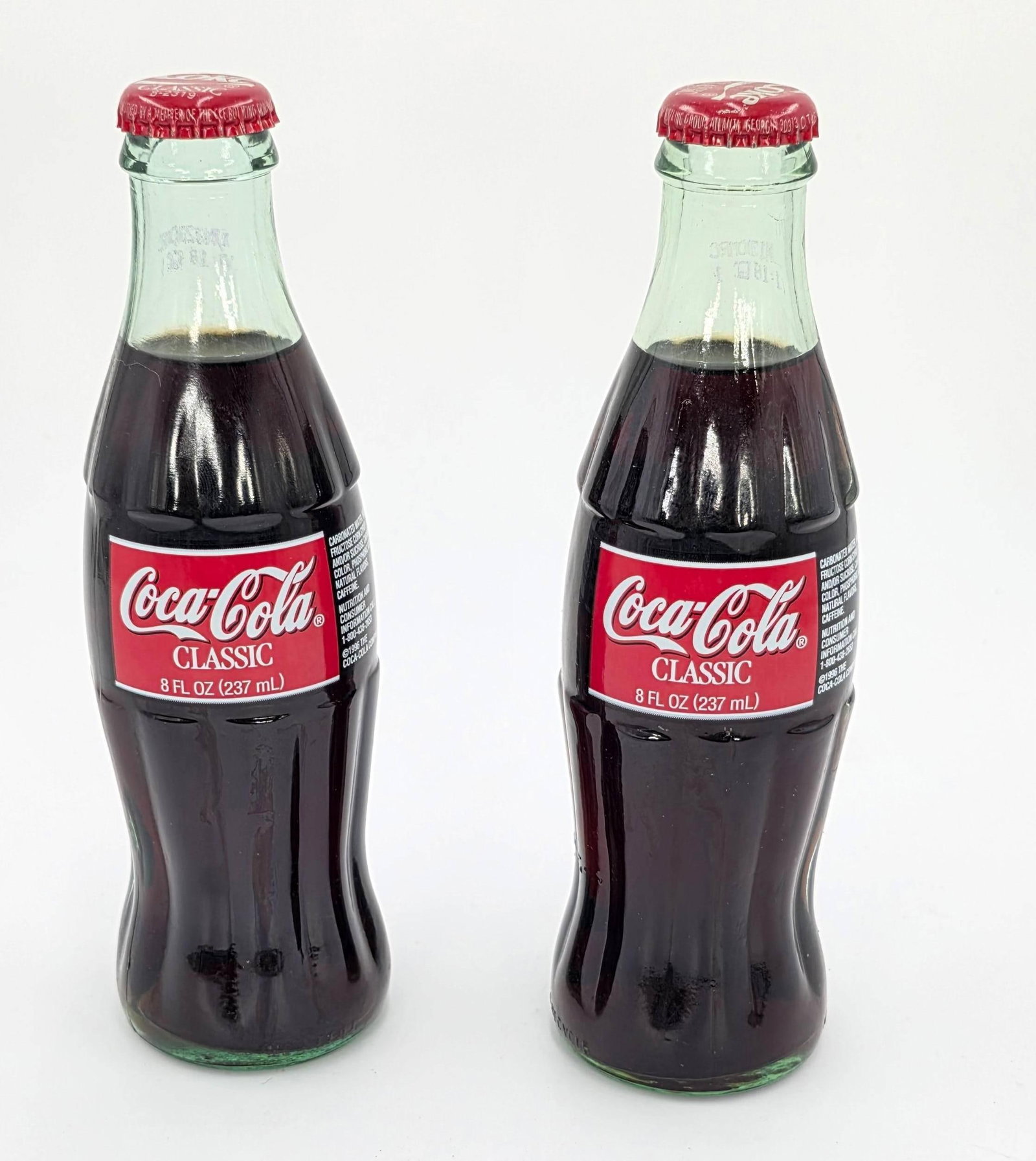 Two 1996 Coke bottles. inv 727, 728: 7.75 x 2.5 x 2.5 inches each