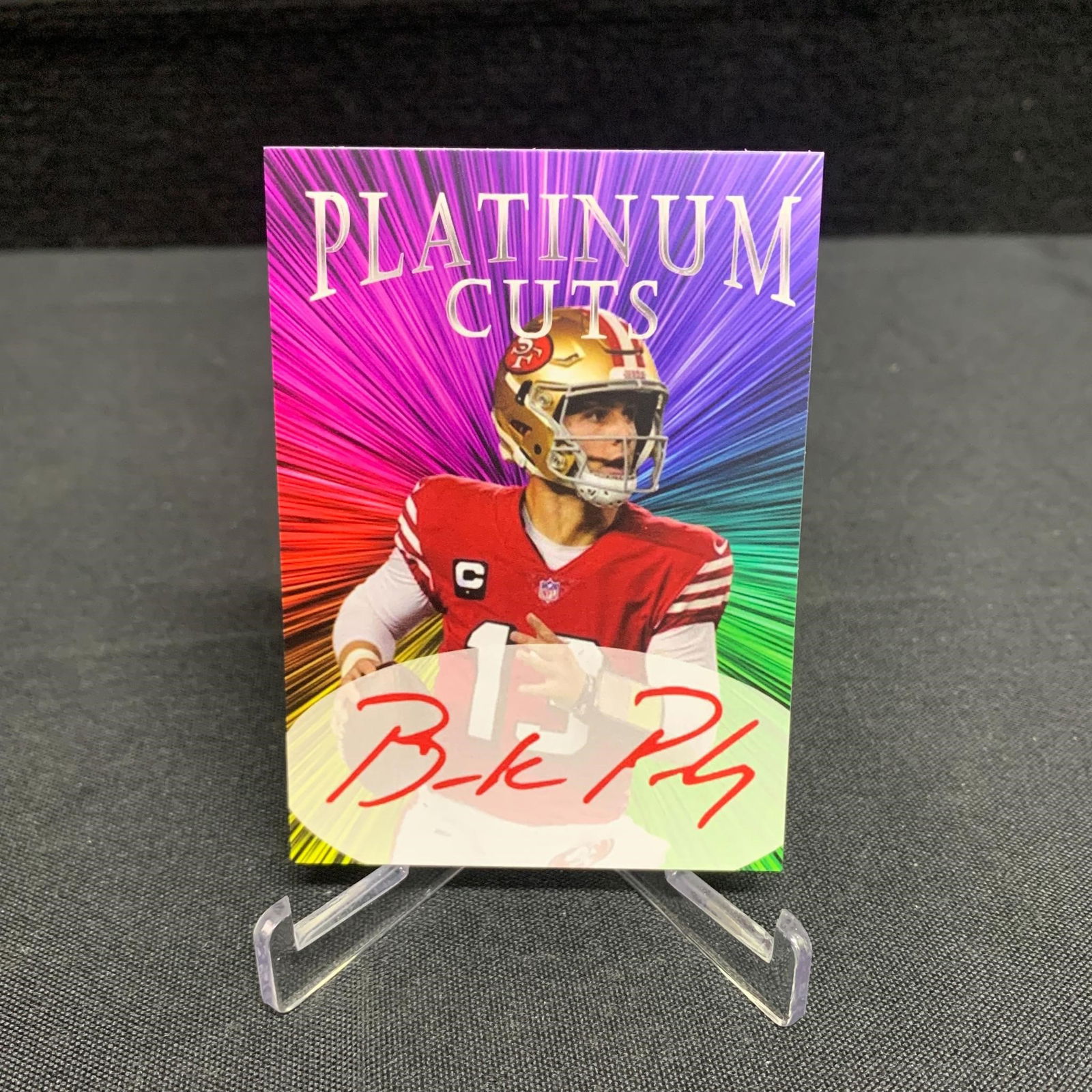 Brok Purdy Platinum Cuts: Iconic Ink cards are the name of the manufacturer of the product and they specialize in sport card sets with facsimile autographs as part of their trading card front. The backs of some of these cards