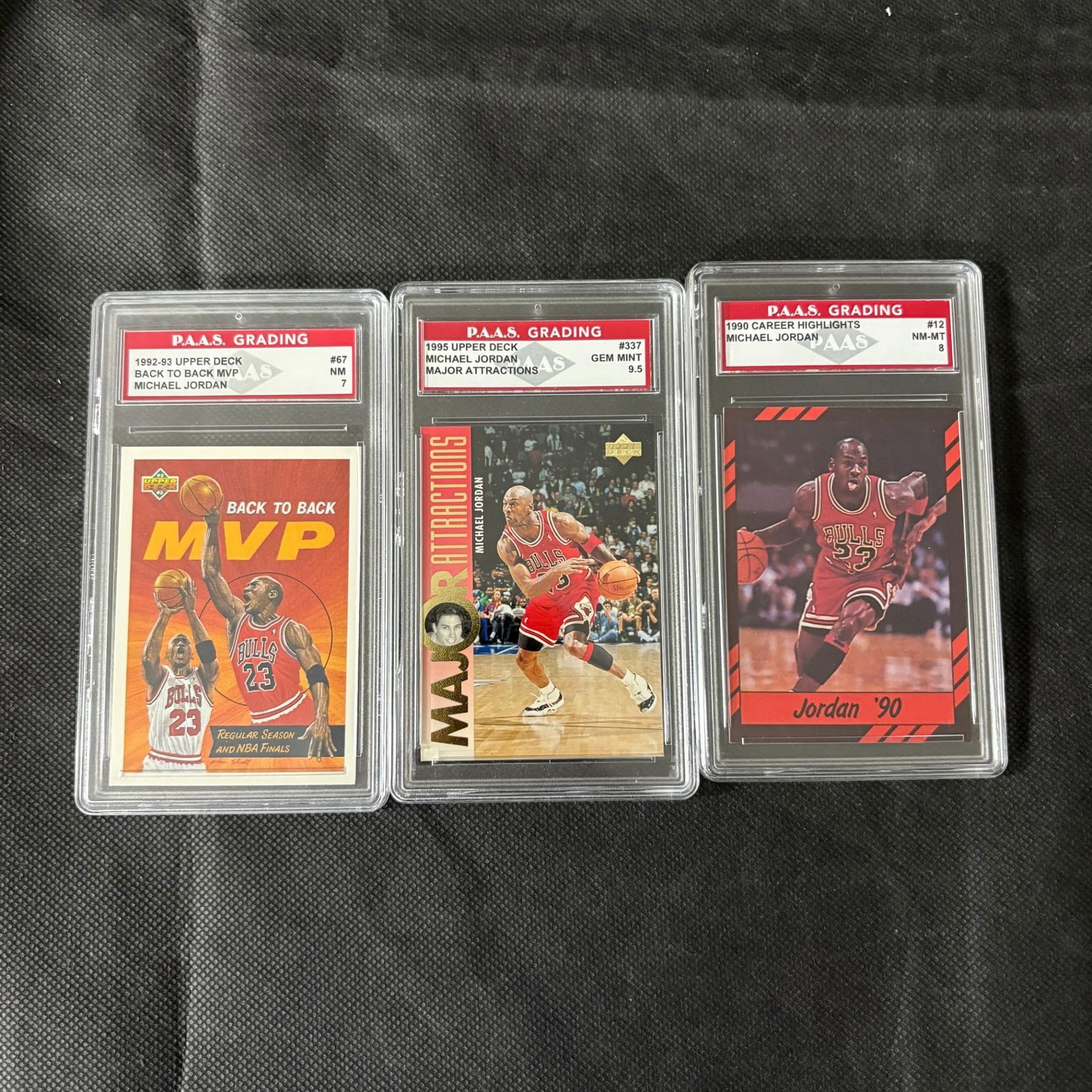 Graded Michael Jordan Basketball Cards: PAAS 7 Michael Jordan #67 Back to Back MVP 1992-93 Upper Deck, PAAS 9.5 Michael Jordan #337 Major Attractions 1995 Upper Deck, and PAAS 8 Michael Jordan #12 1990 Career Highlights. We ship in-house! W