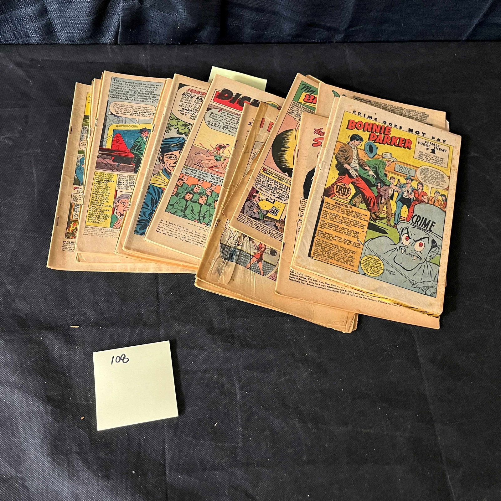 A Collection of Golden Age American True Crime Comic Books, Including 'Crime Does Not Pay' Featuring: A collection of approximately ten vintage American comic books, primarily from the Golden Age period, characterized by sequential art and text printed on aged paper with colored ink. One prominent cov