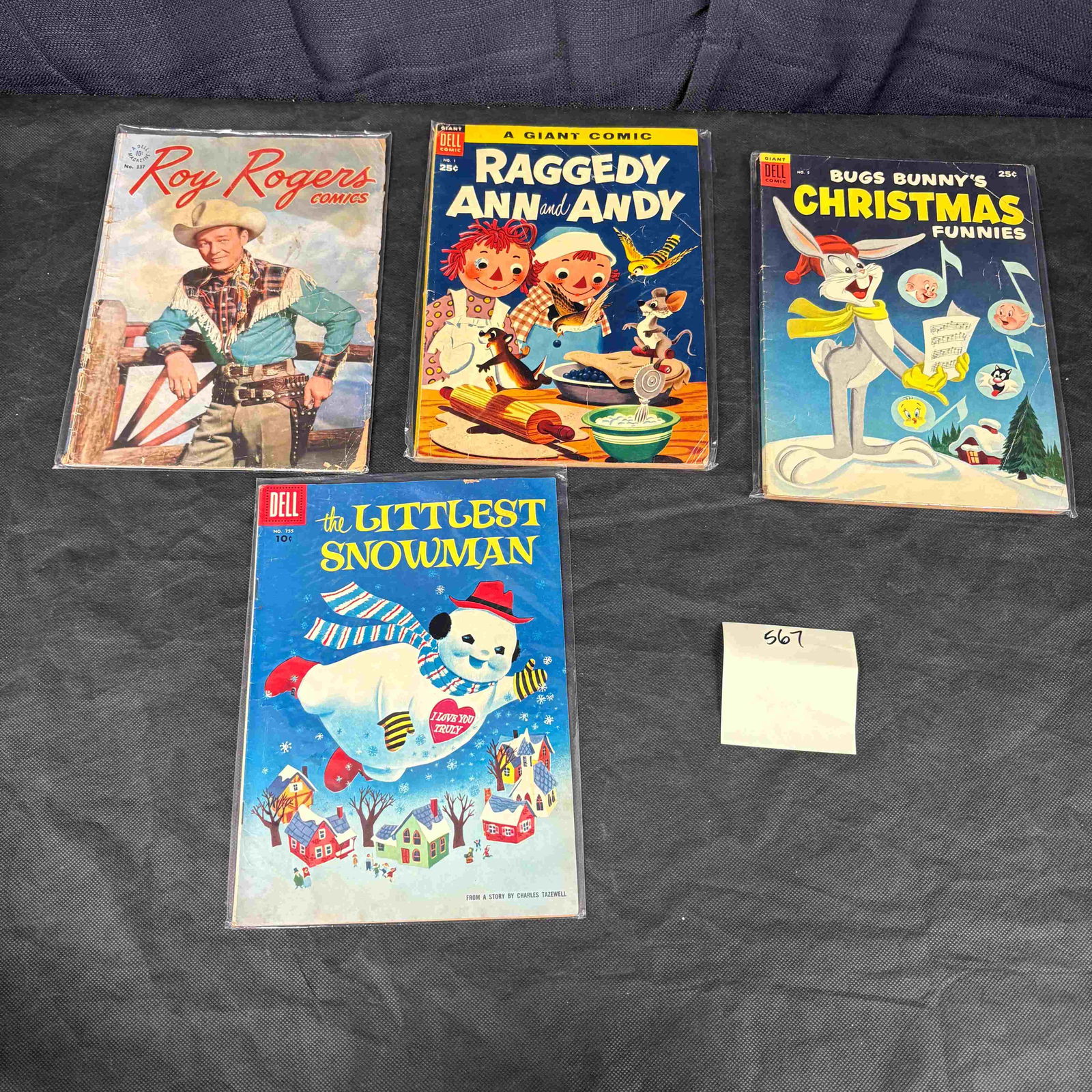 A Group of Four Vintage Dell American Comic Books, including Roy Rogers Comics No. 137, Raggedy Ann: A group of four vintage American comic books, all published by Dell, characteristic of mid-20th century comic illustration. Each comic is housed in a clear plastic protective sleeve. The lot includes