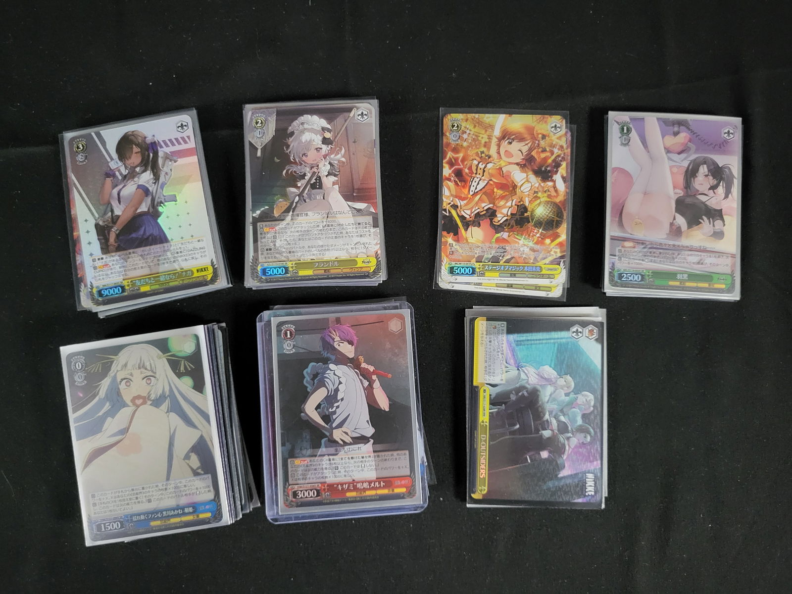 I00110 A Collection of Weiss Schwarz Trading Cards Featuring Oshi no Ko, Goddess of Victory: Nikke,: BID PER WHAT YOU SEE IN THE PHOTO, NOT THE AI GENERATED TITLES AND DESCRIPTIONS! A collection of modern collectible trading cards from the Weiss Schwarz trading card game, produced by Bushiroad. The a