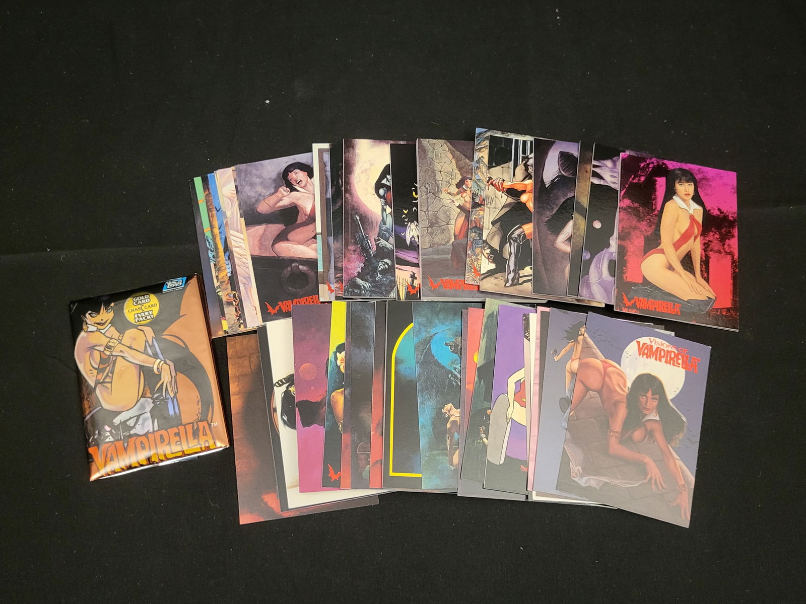 A Collection of Topps Vampirella Trading Cards and Unopened Pack: BID PER WHAT YOU SEE IN THE PHOTO, NOT THE AI GENERATED TITLES AND DESCRIPTIONS! A collection of Topps Vampirella trading cards featuring various artistic representations of the character. The lot inc