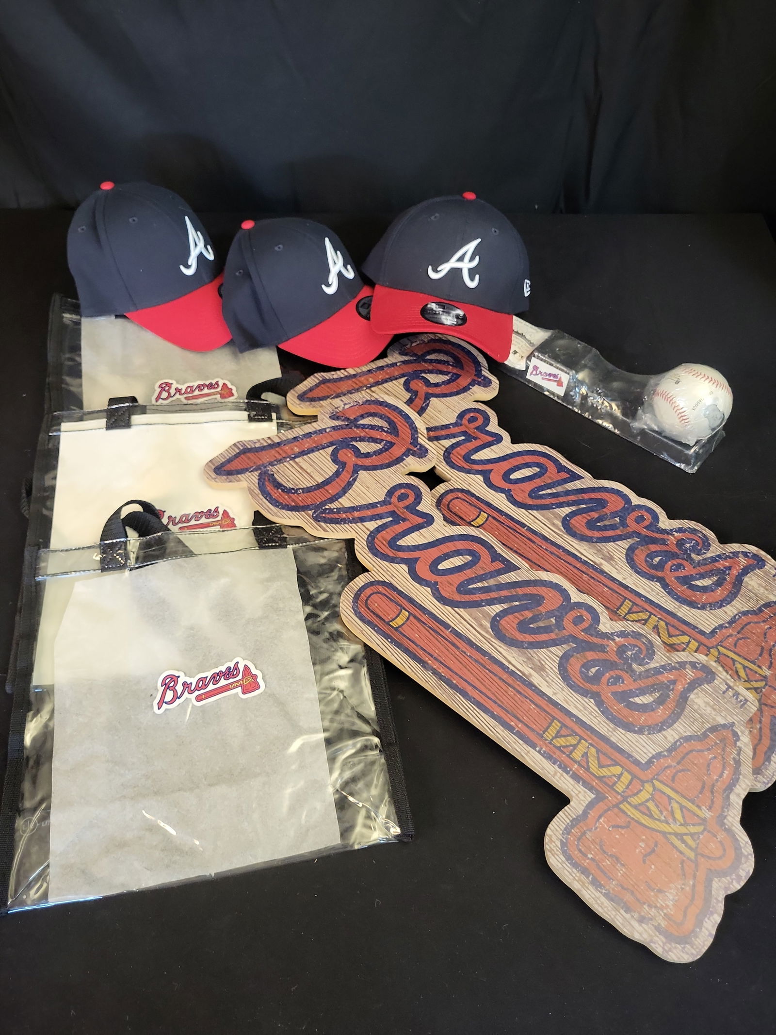 I01063 | Atlanta Braves Memorabilia Lot: A Pair of Wooden Signs, Three New Era Hats, and a Greg Madd: BID PER WHAT YOU SEE IN THE PHOTO, NOT THE AI GENERATED TITLES AND DESCRIPTIONS! Atlanta Braves Memorabilia Lot: A Pair of Wooden Signs, Three New Era Hats, and a Greg Maddux Souvenir Baseball with ML
