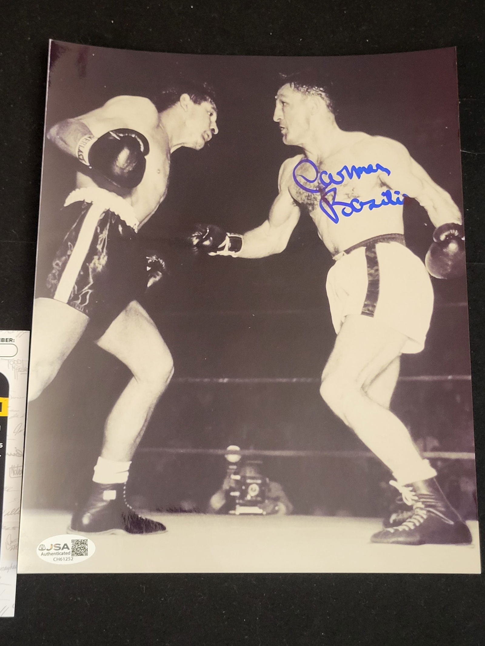I00795 | Carmen Basilio Signed Boxing Photograph with JSA Authentication: BID PER WHAT YOU SEE IN THE PHOTO, NOT THE AI GENERATED TITLES AND DESCRIPTIONS! Carmen Basilio Signed Boxing Photograph with JSA Authentication A black and white glossy photographic print depicting a