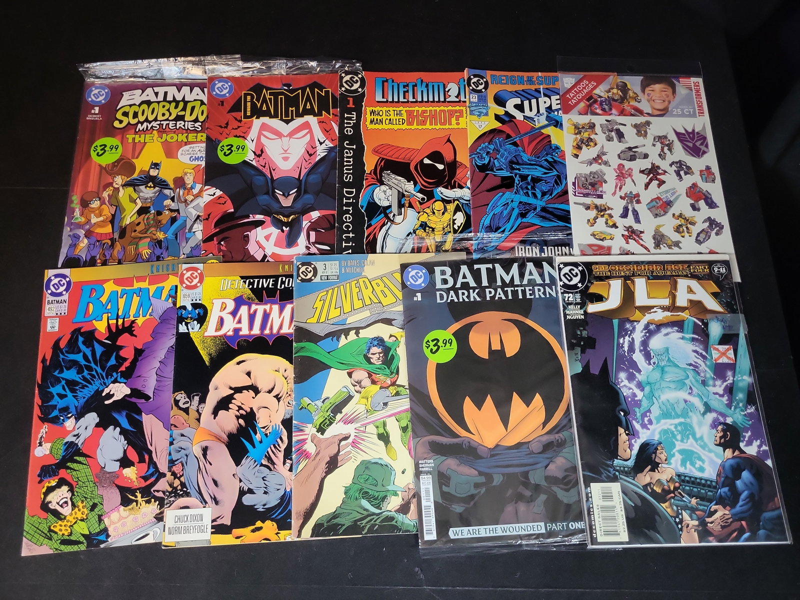 I02935 | A Collection of Nine DC Comics and One Sheet of Transformers Temporary Tattoos: BID PER WHAT YOU SEE IN THE PHOTO, NOT THE AI GENERATED TITLES AND DESCRIPTIONS! A Collection of Nine DC Comics and One Sheet of Transformers Temporary Tattoos This lot contains nine comic books publi