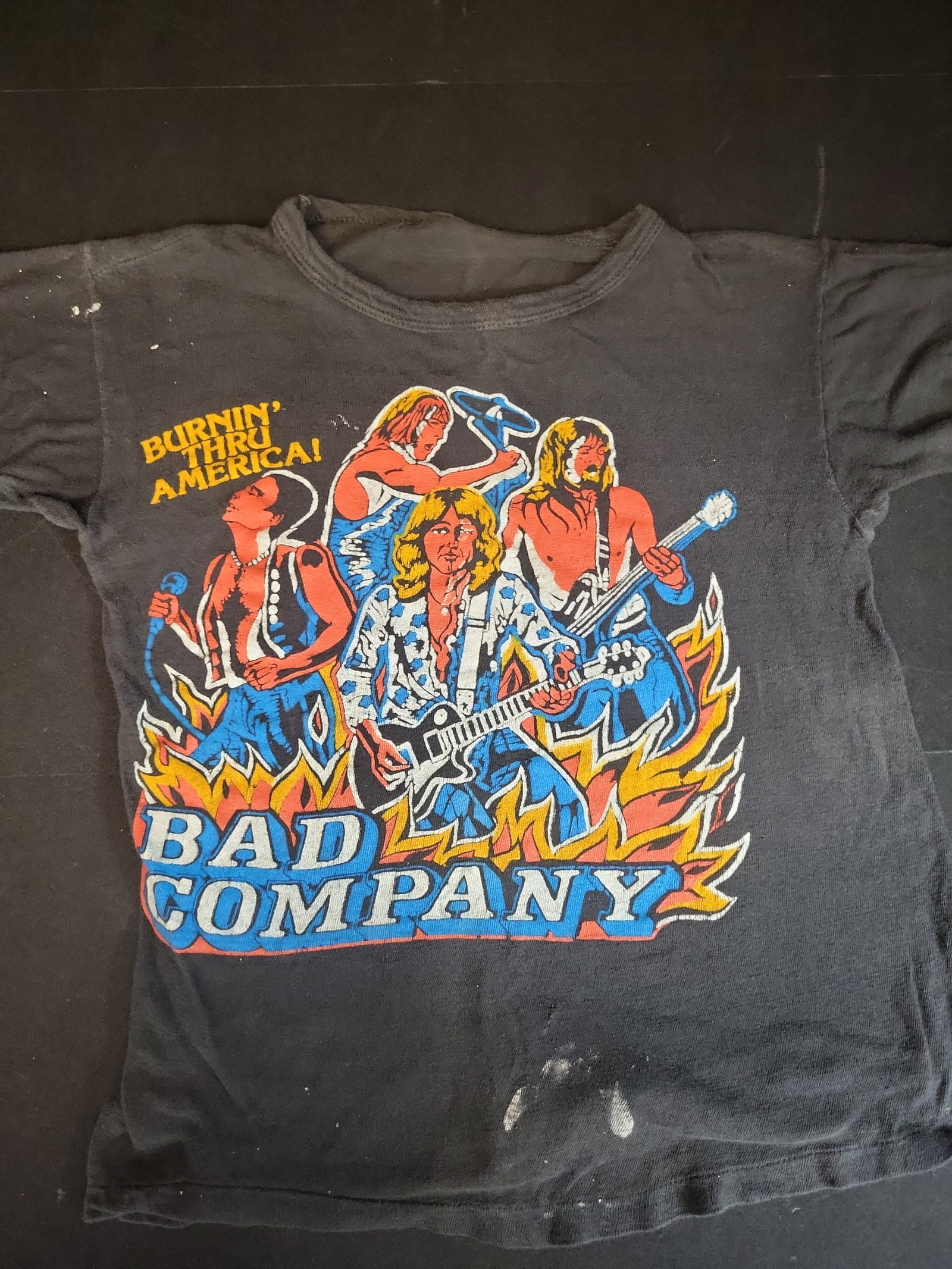 I02756 | Vintage Bad Company Burnin Thru America Concert T-Shirt: BID PER WHAT YOU SEE IN THE PHOTO, NOT THE AI GENERATED TITLES AND DESCRIPTIONS! Vintage Bad Company Burnin Thru America Concert T-Shirt This is a vintage black short-sleeved t-shirt featuring a scree