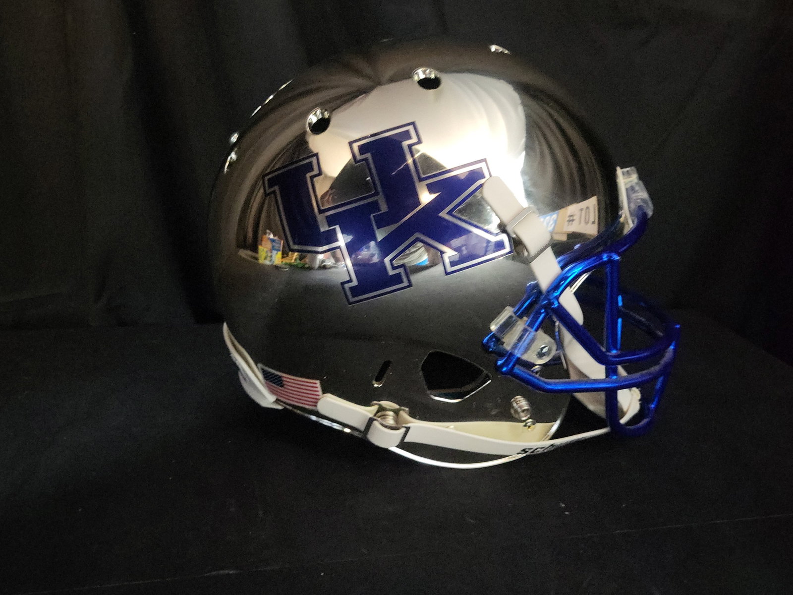 I03212 | Schutt University of Kentucky Wildcats Chrome Replica Football Helmet: BID PER WHAT YOU SEE IN THE PHOTO, NOT THE AI GENERATED TITLES AND DESCRIPTIONS! This is a full-size replica football helmet for the University of Kentucky Wildcats, manufactured by Schutt. The helmet