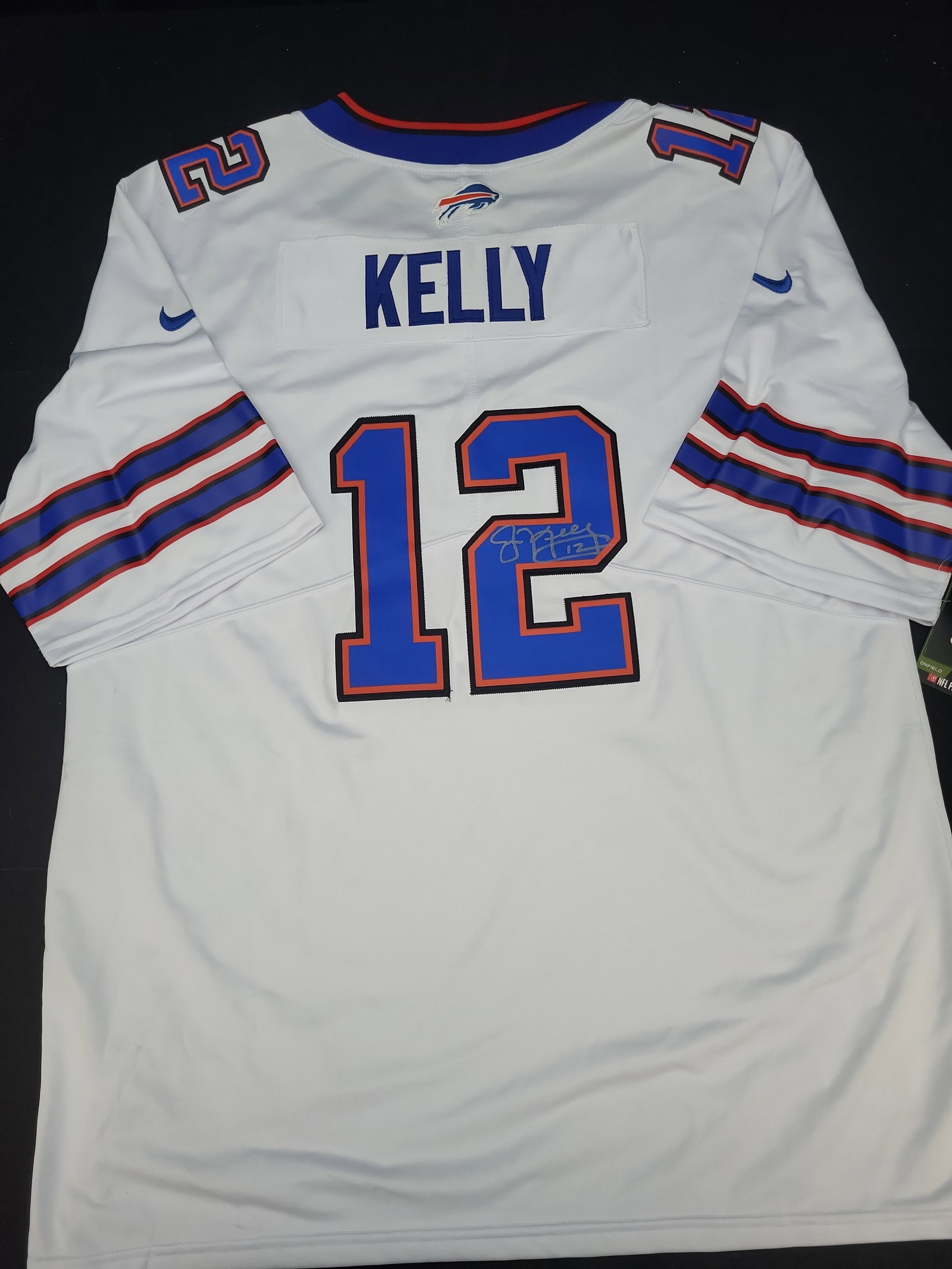 I03560 | Jim Kelly Signed Buffalo Bills Nike Onfield White Jersey: BID PER WHAT YOU SEE IN THE PHOTO, NOT THE AI GENERATED TITLES AND DESCRIPTIONS! Jim Kelly Signed Buffalo Bills Nike Onfield White Jersey This is a white Nike Onfield Buffalo Bills football jersey fea