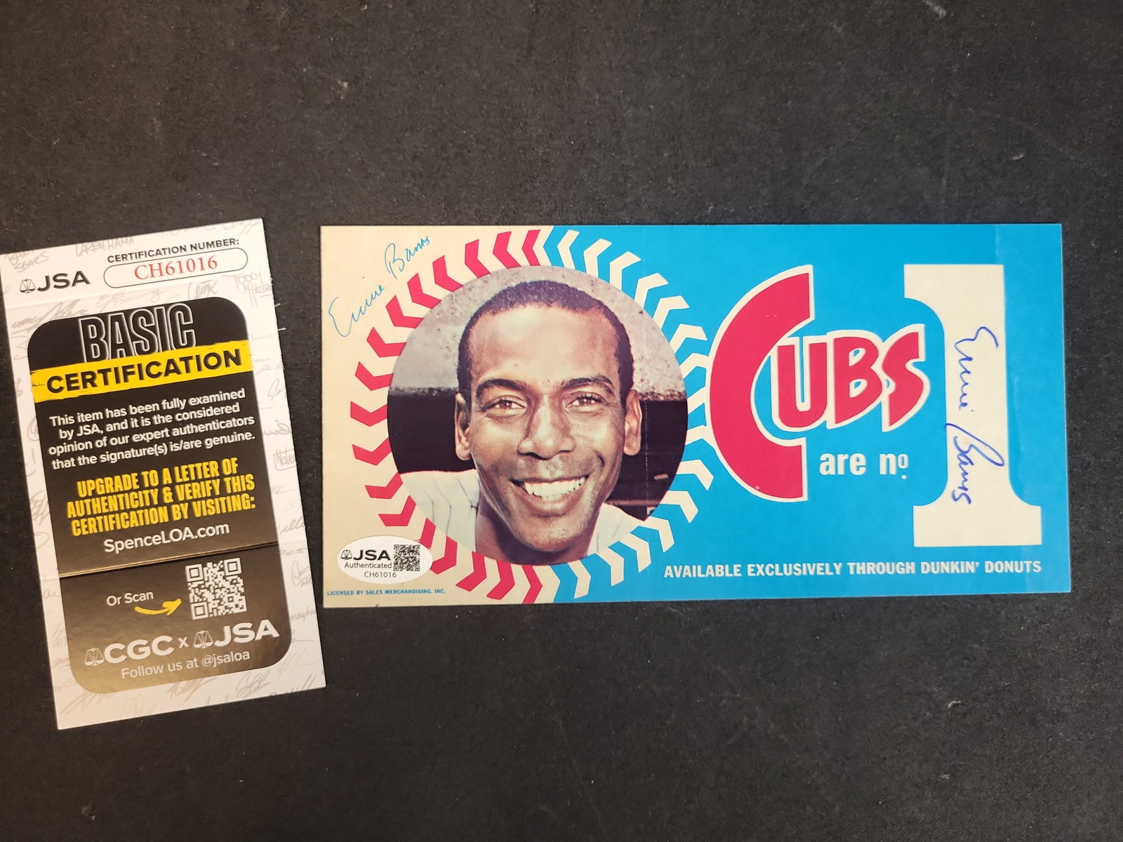 I03307 | Dual Signed 1970 Dunkin Donuts Chicago Cubs Ernie Banks Bumper Sticker JSA COA: BID PER WHAT YOU SEE IN THE PHOTO, NOT THE AI GENERATED TITLES AND DESCRIPTIONS! A vintage 1970 Chicago Cubs promotional bumper sticker featuring Baseball Hall of Famer Ernie Banks, dual-signed by the