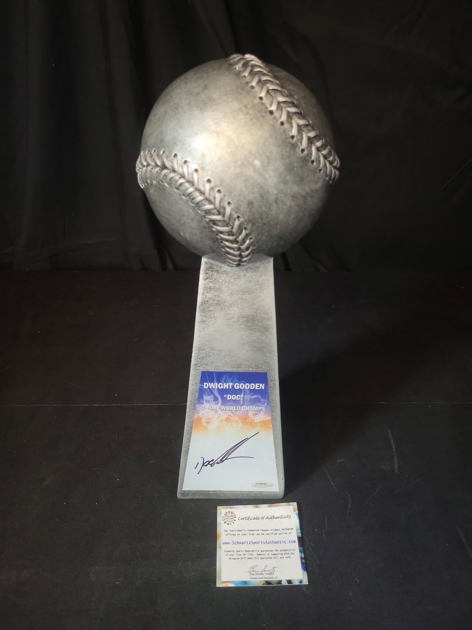 I03119 | Dwight Doc Gooden Signed 14-Inch Replica Silver World Champion Baseball Trophy: BID PER WHAT YOU SEE IN THE PHOTO, NOT THE AI GENERATED TITLES AND DESCRIPTIONS! Dwight Doc Gooden Signed 14-Inch Replica Silver World Champion Baseball Trophy This commemorative baseball sculpture is