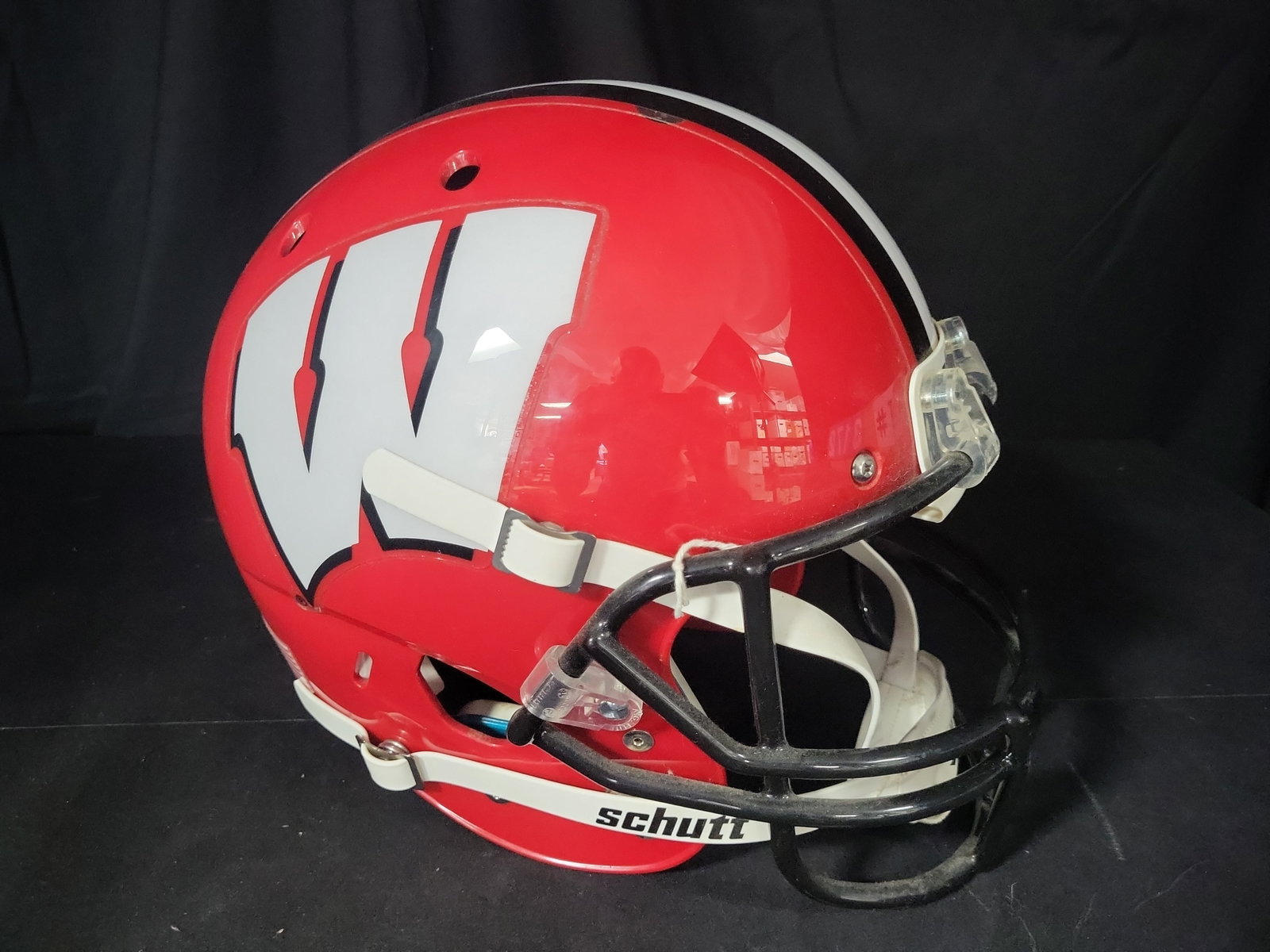 I03172 | University of Wisconsin Badgers Schutt Full Size Replica Football Helmet: BID PER WHAT YOU SEE IN THE PHOTO, NOT THE AI GENERATED TITLES AND DESCRIPTIONS! This University of Wisconsin Badgers full-size display football helmet is manufactured by Schutt. The item features a g