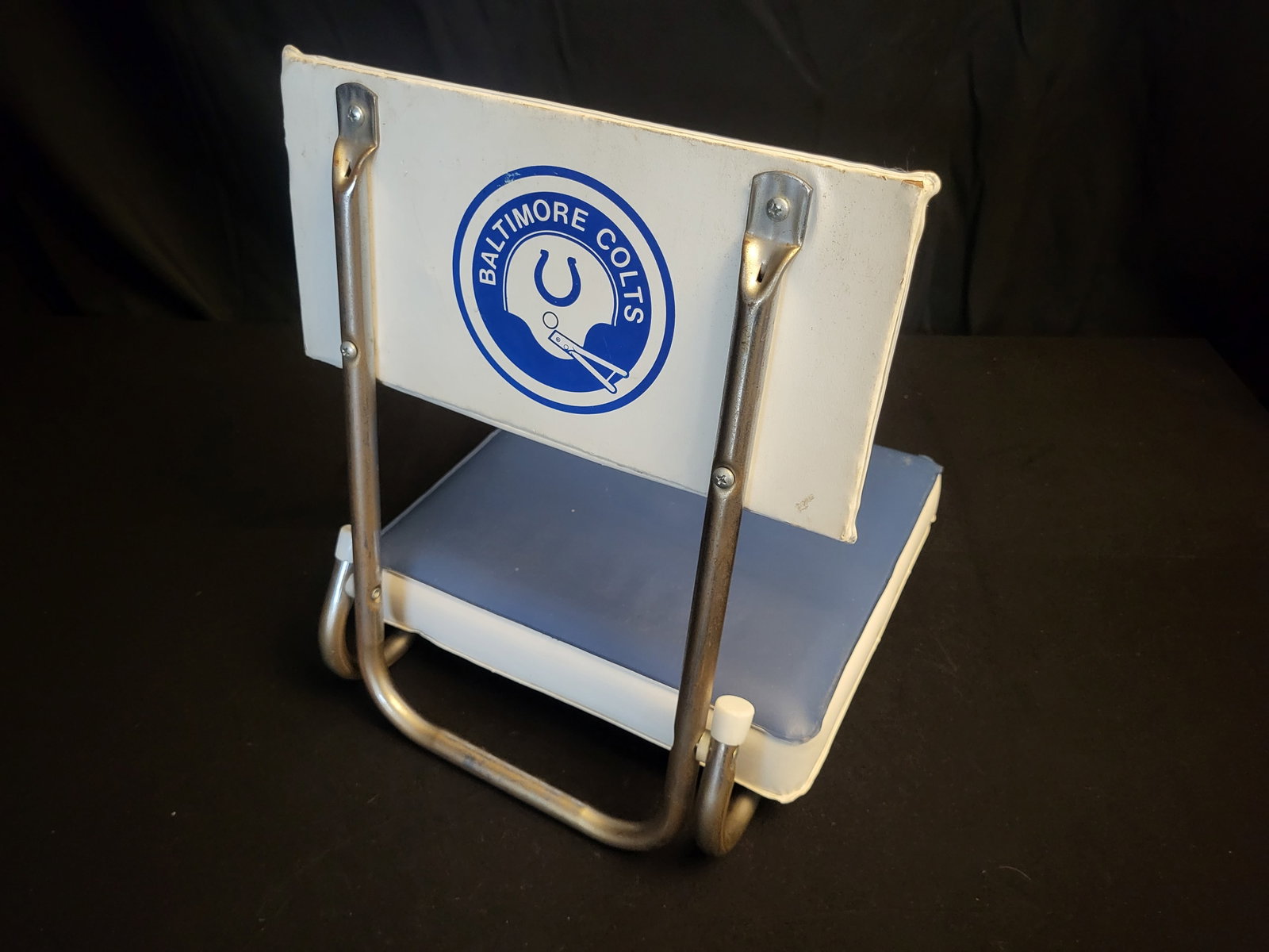 I00586 | Vintage Baltimore Colts Folding Stadium Seat: BID PER WHAT YOU SEE IN THE PHOTO, NOT THE AI GENERATED TITLES AND DESCRIPTIONS! Vintage Baltimore Colts Folding Stadium Seat This vintage portable stadium bleacher seat features the logo for the Balt