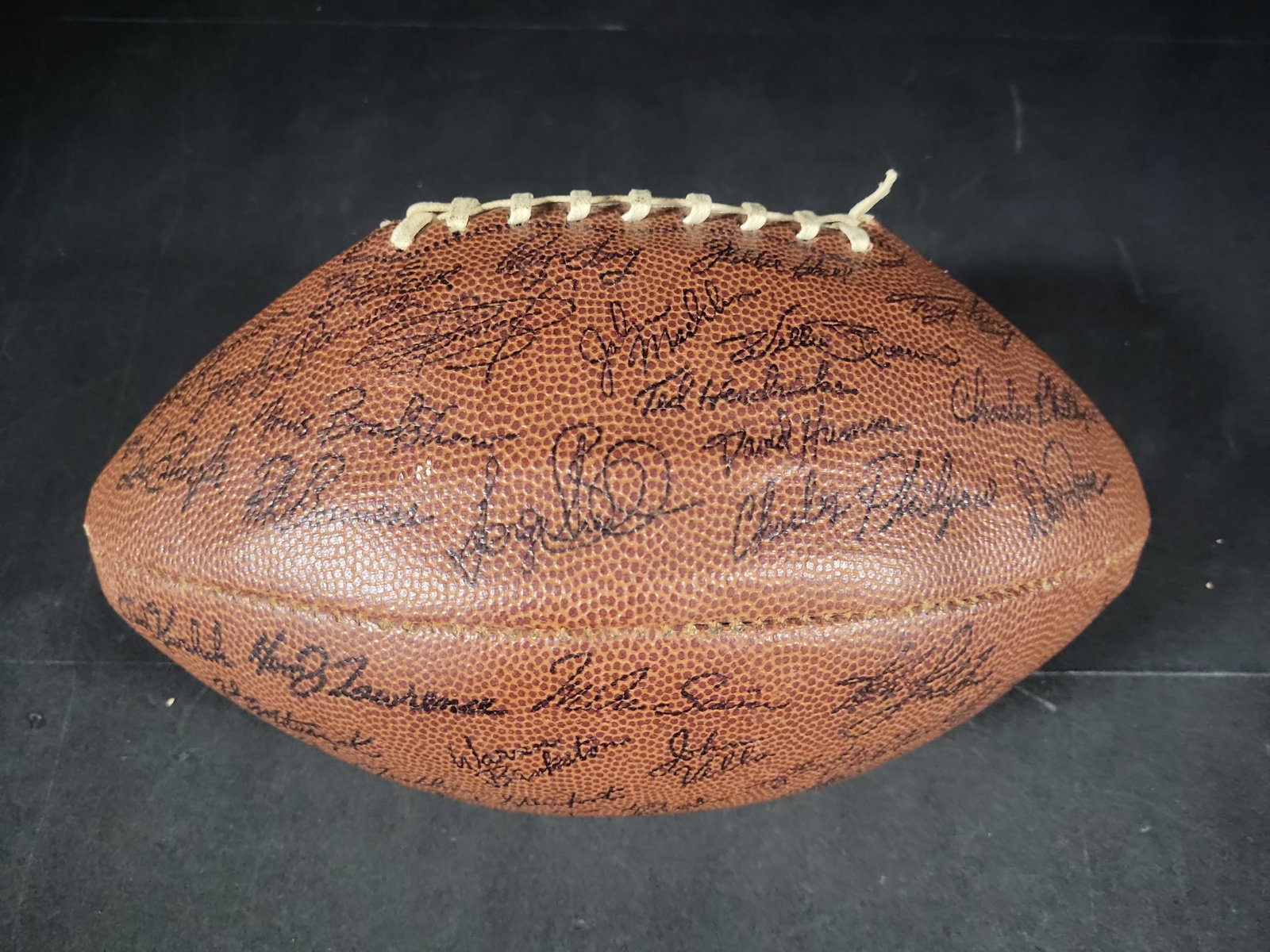 I03189 | Oakland Raiders Vintage Souvenir Football with Facsimile Signatures: BID PER WHAT YOU SEE IN THE PHOTO, NOT THE AI GENERATED TITLES AND DESCRIPTIONS! A vintage Oakland Raiders NFL souvenir football from the mid-to-late 1970s. The brown pebbled-texture football features