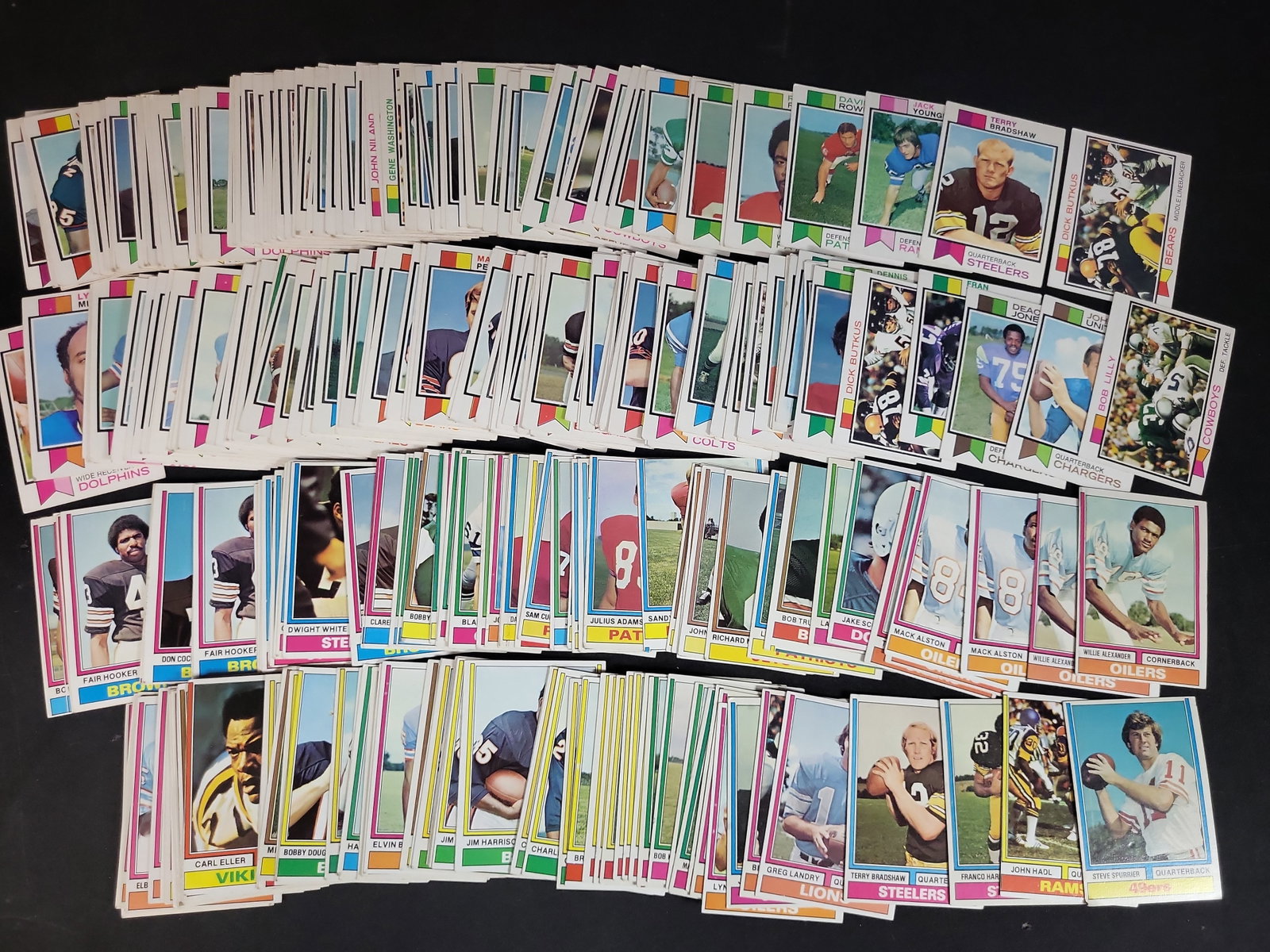 I03872 | A Collection of 1973 Topps Football Cards Featuring Terry Bradshaw and Franco Harris Rookie: BID PER WHAT YOU SEE IN THE PHOTO, NOT THE AI GENERATED TITLES AND DESCRIPTIONS! This lot comprises a large collection of vintage 1973 Topps American football trading cards. The cards feature the dist