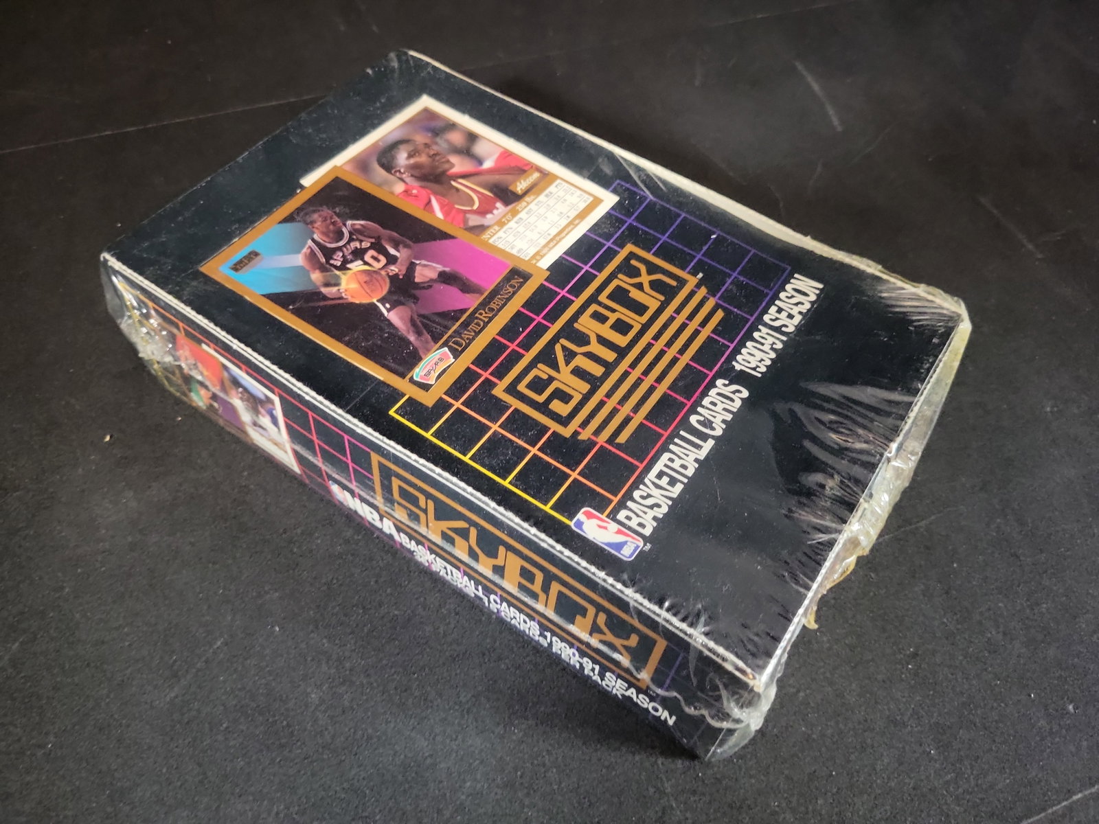 I03243 | 1990-91 SkyBox NBA Basketball Cards Factory-Sealed Wax Box: BID PER WHAT YOU SEE IN THE PHOTO, NOT THE AI GENERATED TITLES AND DESCRIPTIONS! A factory-sealed display box of SkyBox NBA basketball cards from the 1990-91 season. This inaugural release from SkyBox