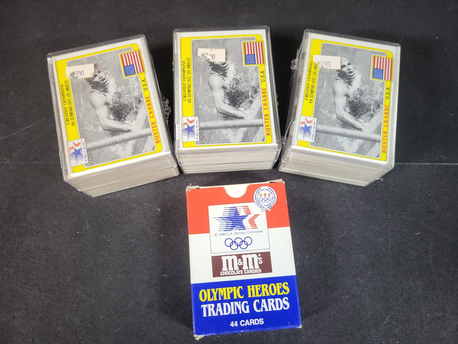 I03249 | A Group of 1983-1984 M&M's Olympic Trading Card Sets and Original Box Including Cassius: BID PER WHAT YOU SEE IN THE PHOTO, NOT THE AI GENERATED TITLES AND DESCRIPTIONS! A group of vintage sports trading cards issued by M&M's Chocolate Candies in association with the 1984 Los Angeles Olym