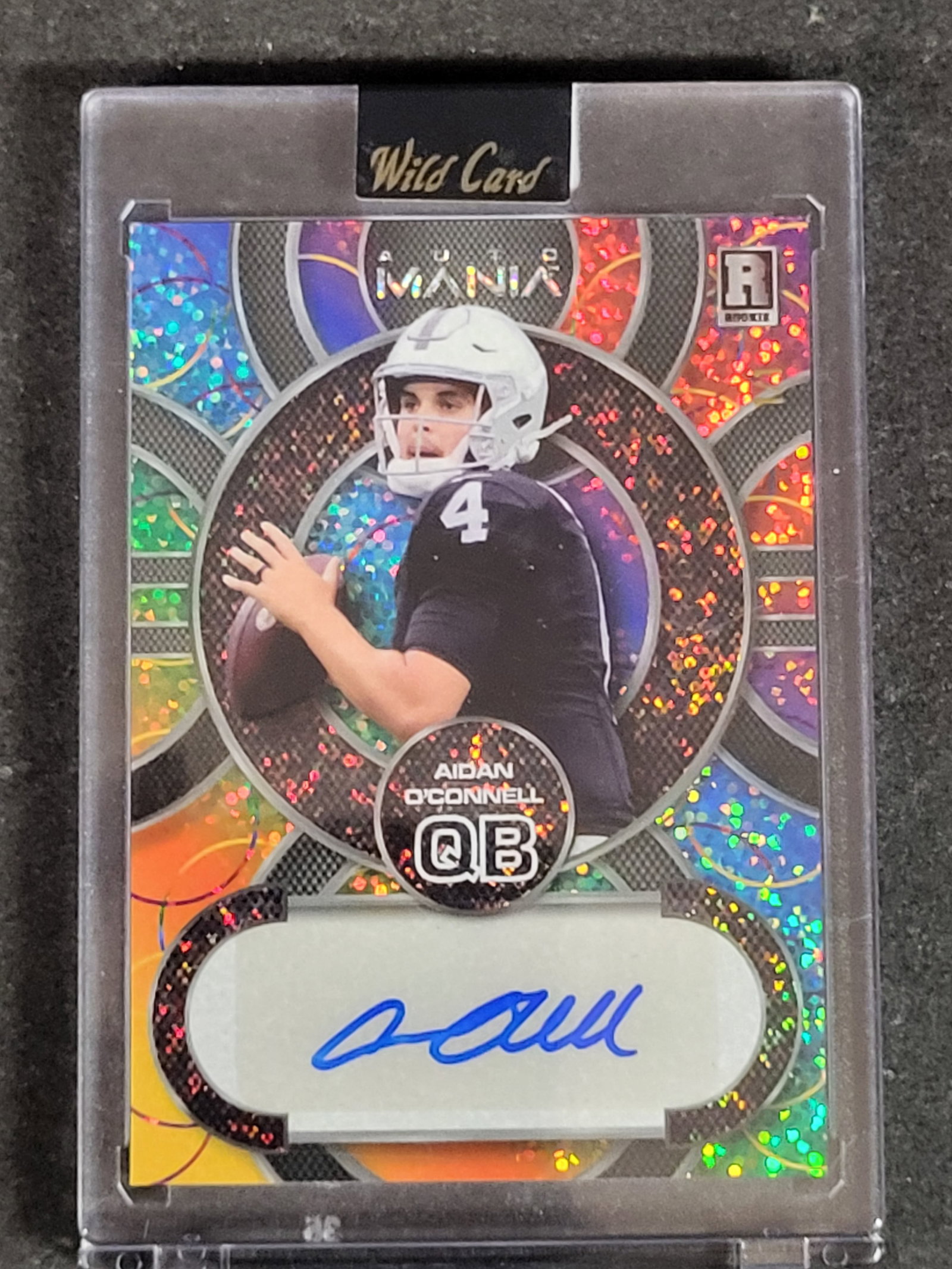 I03892 | 2023 Wild Card Auto Mania Aidan O'Connell Rookie Autograph Card AMC-A Serial Numbered 35: BID PER WHAT YOU SEE IN THE PHOTO, NOT THE AI GENERATED TITLES AND DESCRIPTIONS! This is a 2023 Wild Card Auto Mania football trading card featuring quarterback Aidan O'Connell. The card is identified