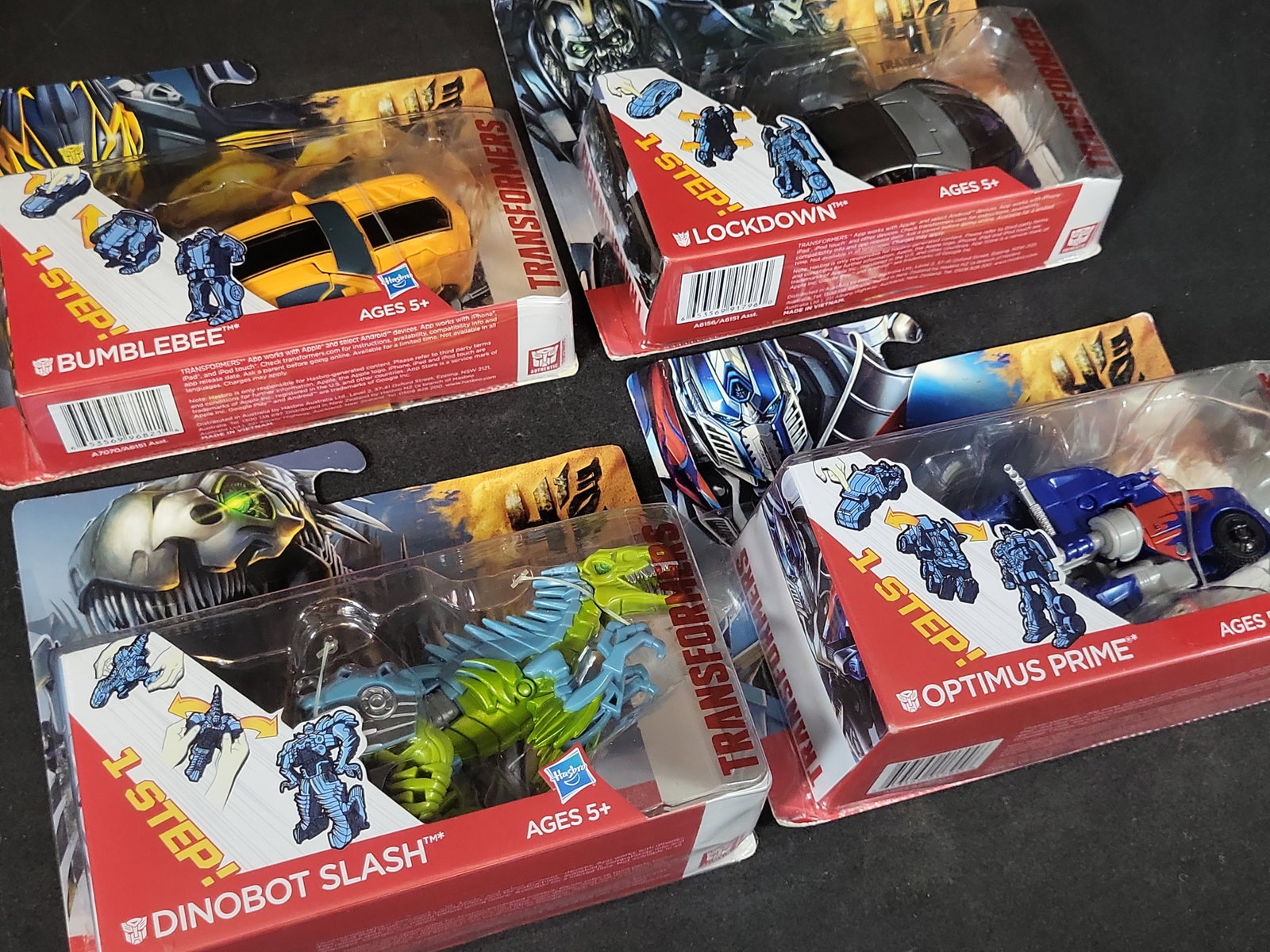 I03519 | Four Hasbro Transformers Age of Extinction 1-Step Changers Action Figures: BID PER WHAT YOU SEE IN THE PHOTO, NOT THE AI GENERATED TITLES AND DESCRIPTIONS! Four Hasbro Transformers Age of Extinction 1-Step Changers Action Figures A collection of four original Transformers: A