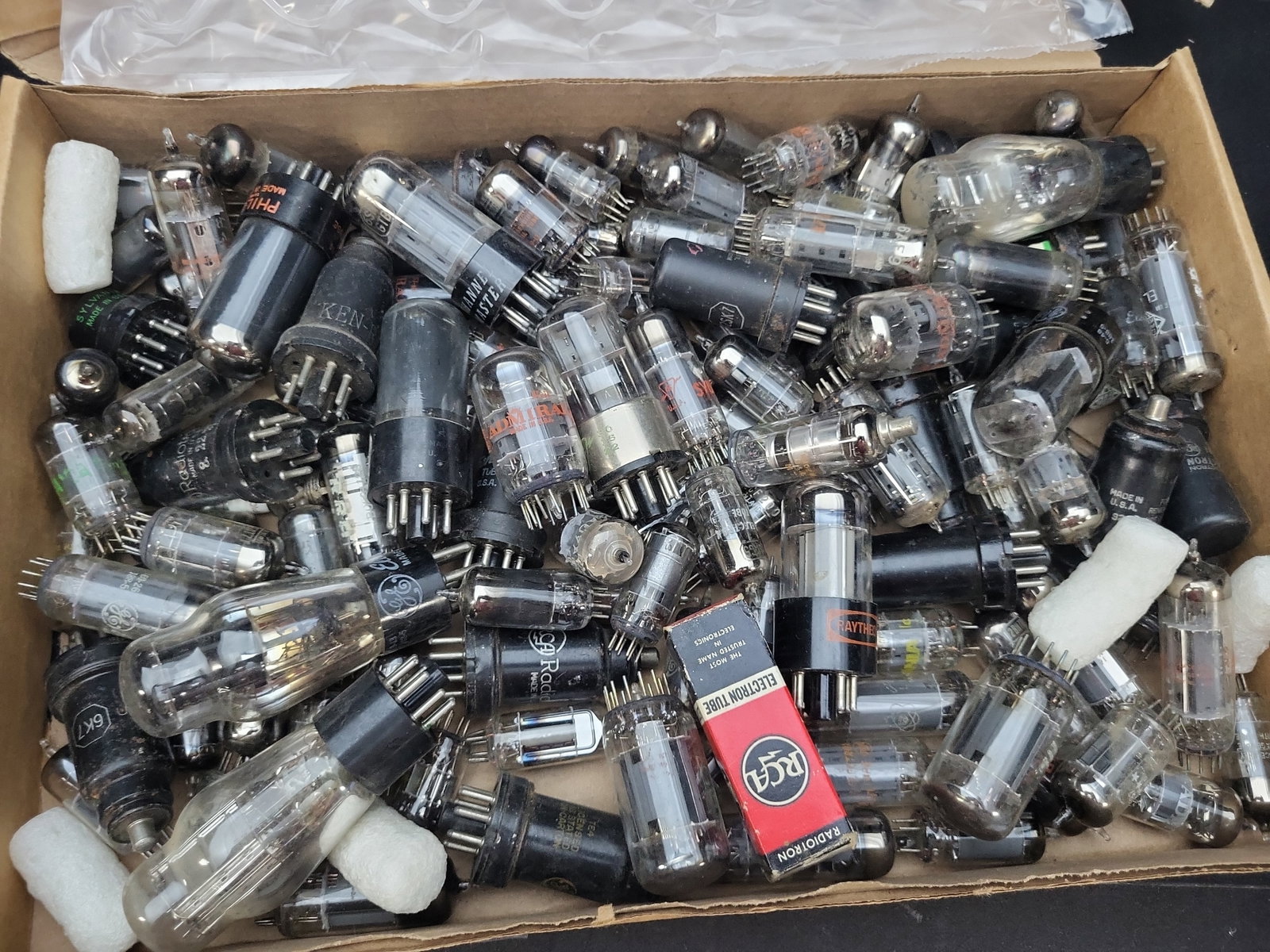 I03332 | An Assortment of Estimated 75 to 100 Vintage Vacuum Tubes: BID PER WHAT YOU SEE IN THE PHOTO, NOT THE AI GENERATED TITLES AND DESCRIPTIONS! A bulk estate lot containing an estimated 75 to 100 vintage vacuum tubes, primarily of mid-20th-century American manufa