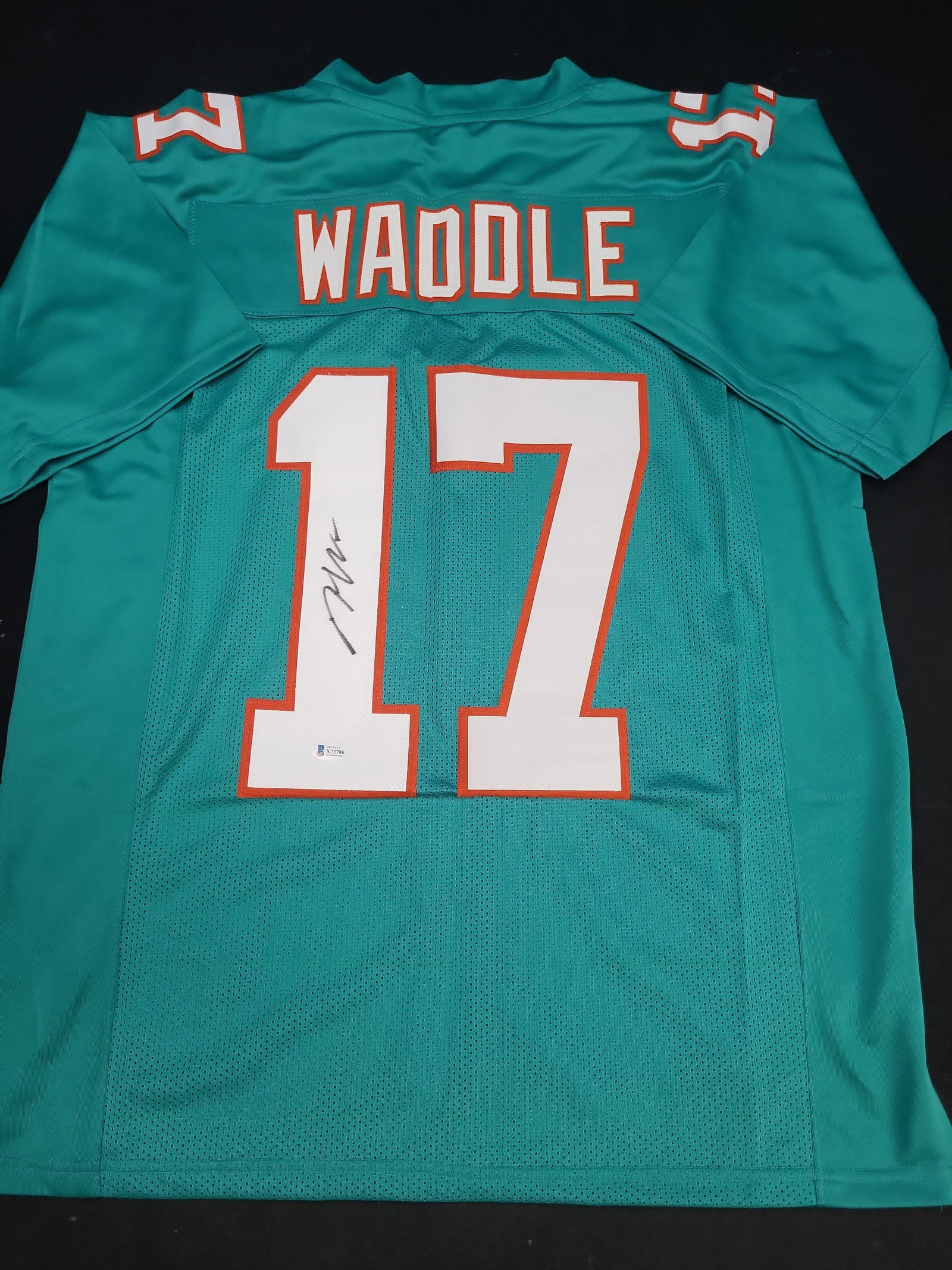 I04325 | Jaylen Waddle Signed Dolphins Jersey Beckett: IMPORTANT â€“ PLEASE REVIEW BEFORE BIDDING: Aeron House makes every effort to accurately identify and describe each lot; however, titles and descriptions may contain errors, omissions, or AI-a