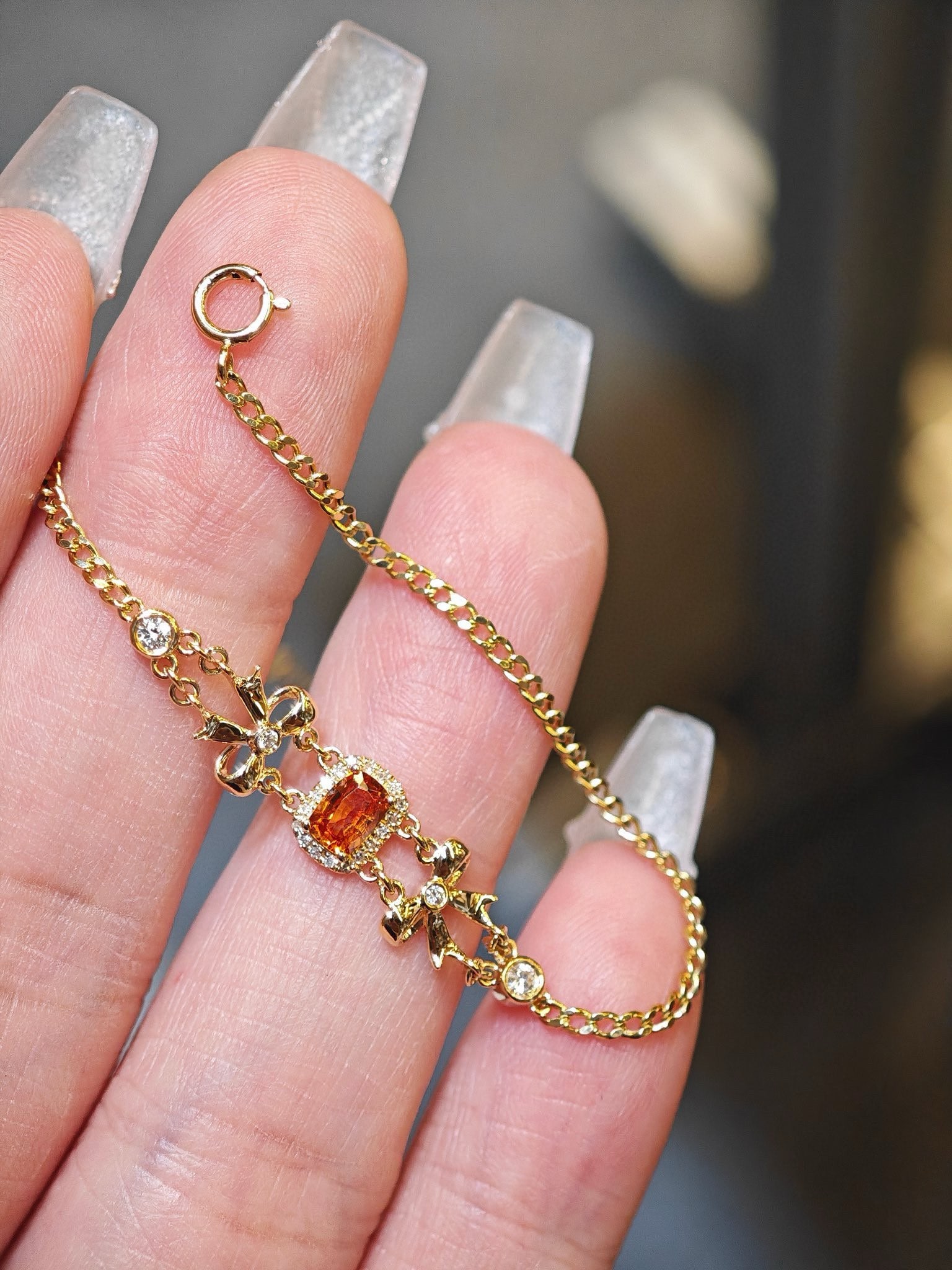 18k Fanta Stone Butterfly Diamond Bracelet: This bracelet features a sweet orange Fanta stone, surrounded by diamonds, with a sophisticated and upscale design. It is adorned with sweet bow ties on both sides and paired with a textured Cuban cha