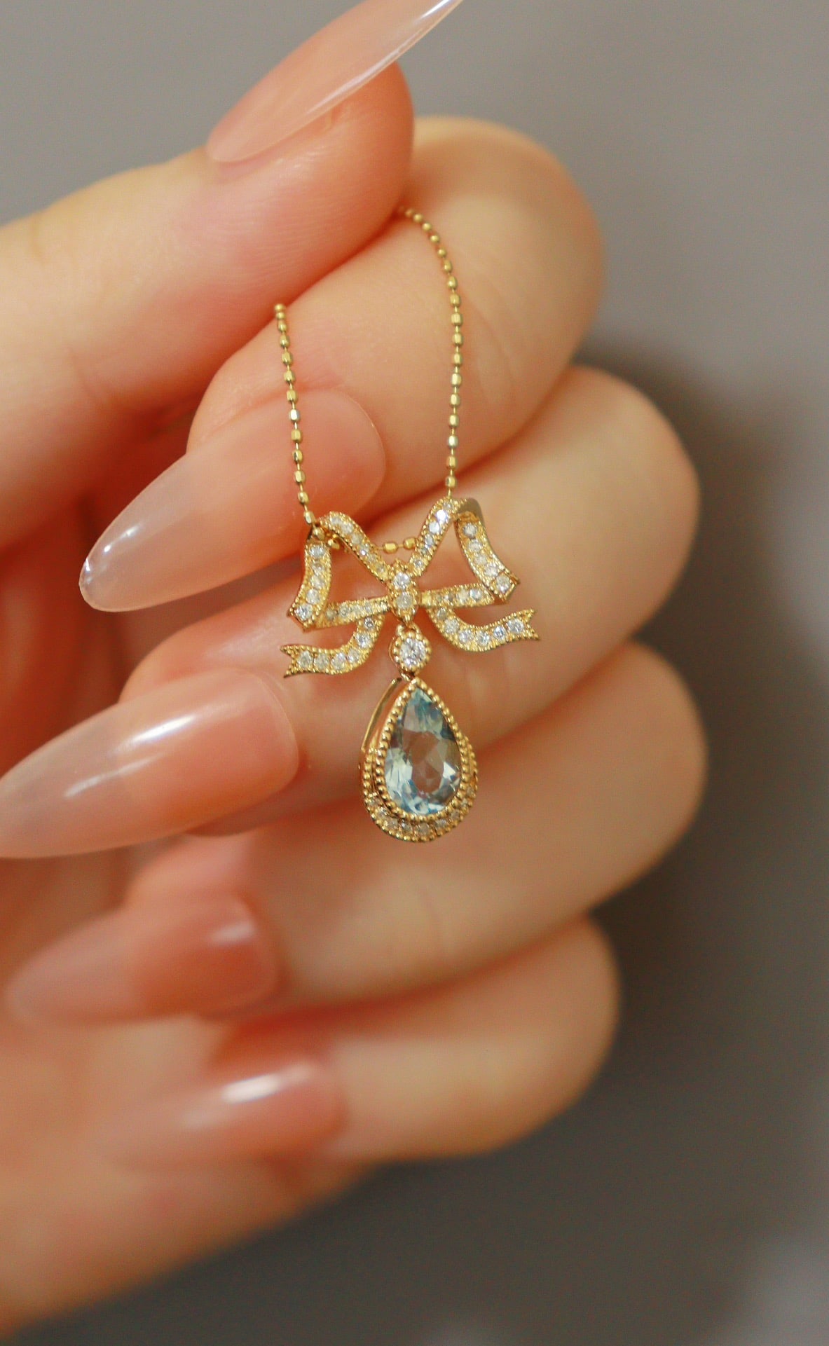 18K Aquamarine Bow Pendant: A 18K gold ribbon bow design, with a teardrop-shaped aquamarine gemstone of approximately 70 points, fully diamond-set, total diamond weight 22 points. Exquisite girlish feel, with a courtly retro vib