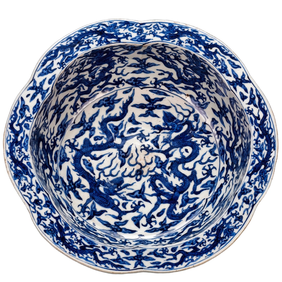 Ming Jiajing Blue and White Cloud Dragon Pattern Melon Ridge Basin: In the Jiajing period of the Ming Dynasty, a blue and white "Cloud-piercing Dragon" patterned melon ribbed basin. The overall design is fully painted with blue and white underglaze cobalt material, wi