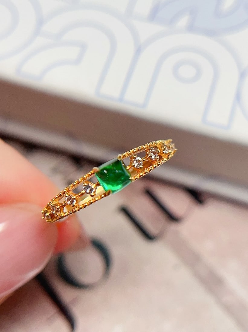 18K Gold Emerald Ring: This ring is meticulously crafted in 18K gold, featuring a natural emerald that exudes a perfect blend of rich gold and cool white. The centerpiece is approximately 0.3 carats, surrounded by 8 white s
