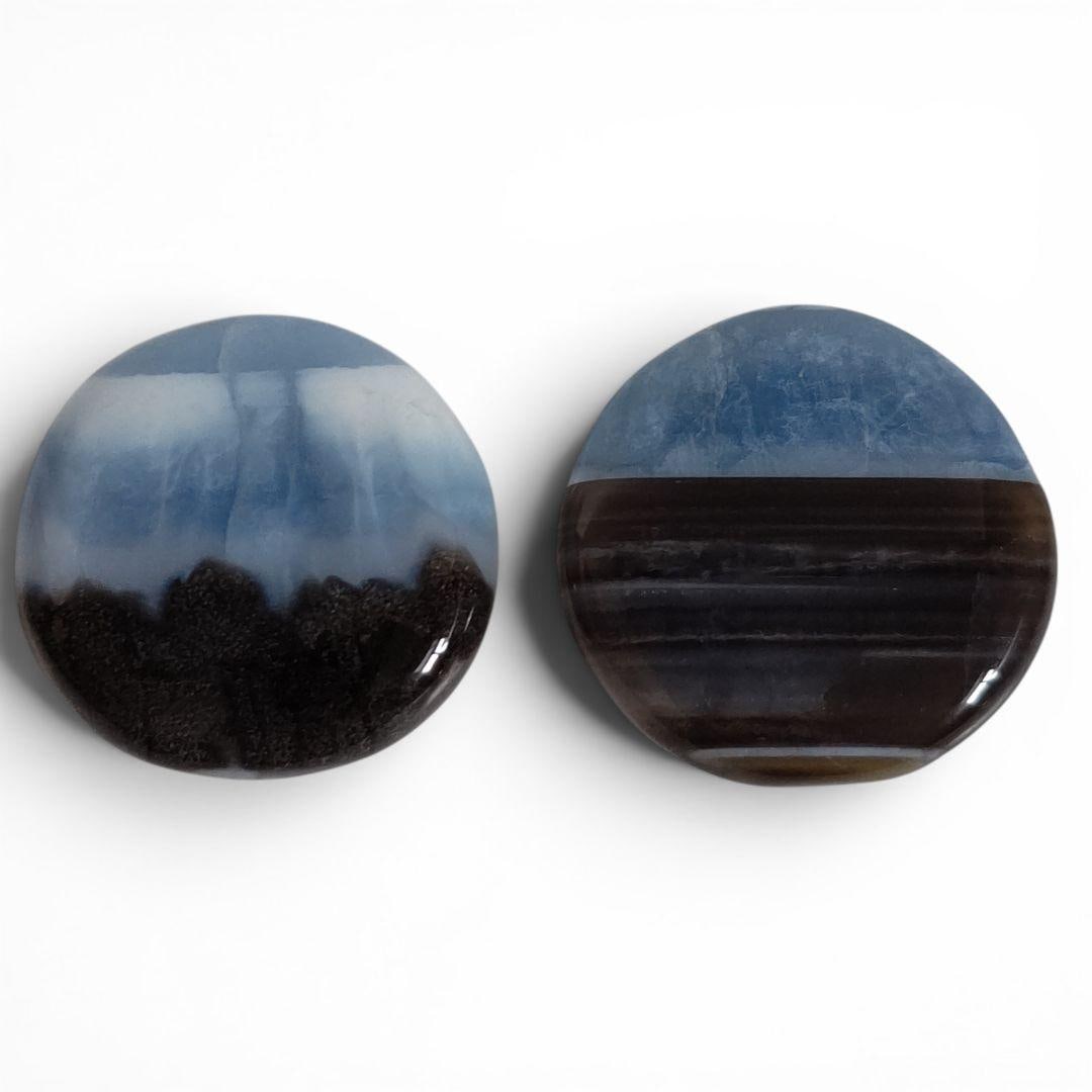 Owyhee Blue Opal Natural Stone: Owyhee Blue Opal Natural Stones, Round, Set of Two, Handheld Stones These stones feature a soft blue as the primary color, accented with brown and black hues. One of the stones exhibits a slightly tra