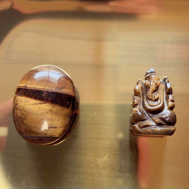 Tiger's Eye Natural Stone and Tiger's Eye Ganesha Statue: Tiger's Eye Natural Palm Stone and Tiger's Eye Ganesha Statue This is a set comprising a Tiger's Eye palm stone and a Ganesha statue. Palm Stone (Hand Stone) The stone boasts a lustrous sheen and smoo
