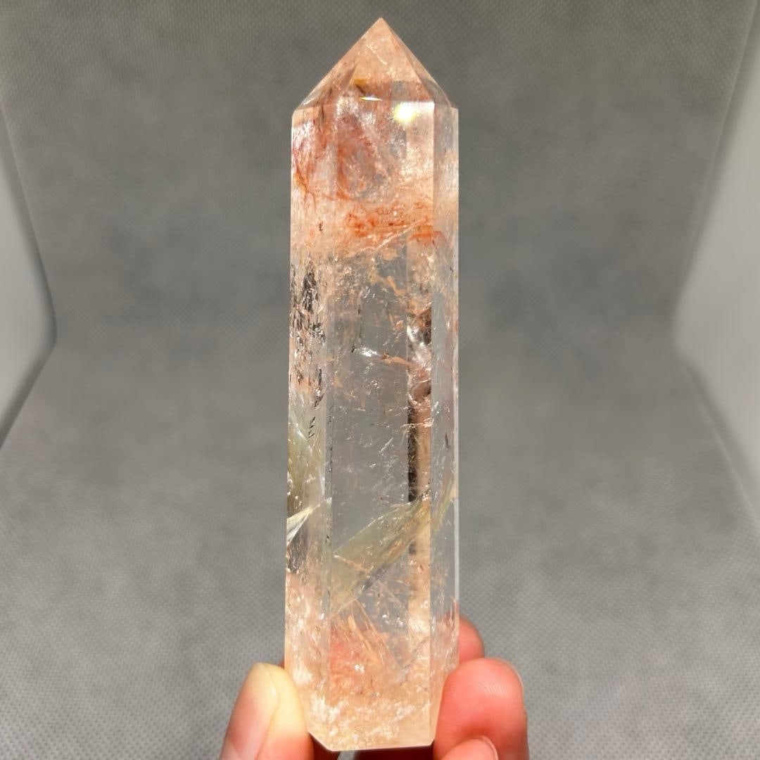 Transparent Pink Aztec Stone Pointed Hexagonal Column Pink Fire Quartz: Transparent Pink Aztec Stone Hexagonal Prism Pink Fire Quartz Dimensions: Height 10.1 cm, Diameter 2.8 cm, Weight: 105 grams Slightly orange-tinted It is visible. The actual color leans towards red.