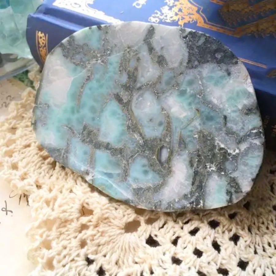 Larimar Cutting Board: Larimar Cutting Slab This is an unpolished piece of Larimar stone, showcasing a beautiful contrast of blue hues with a charming floral pattern spreading across it. It can be used for crafting loose