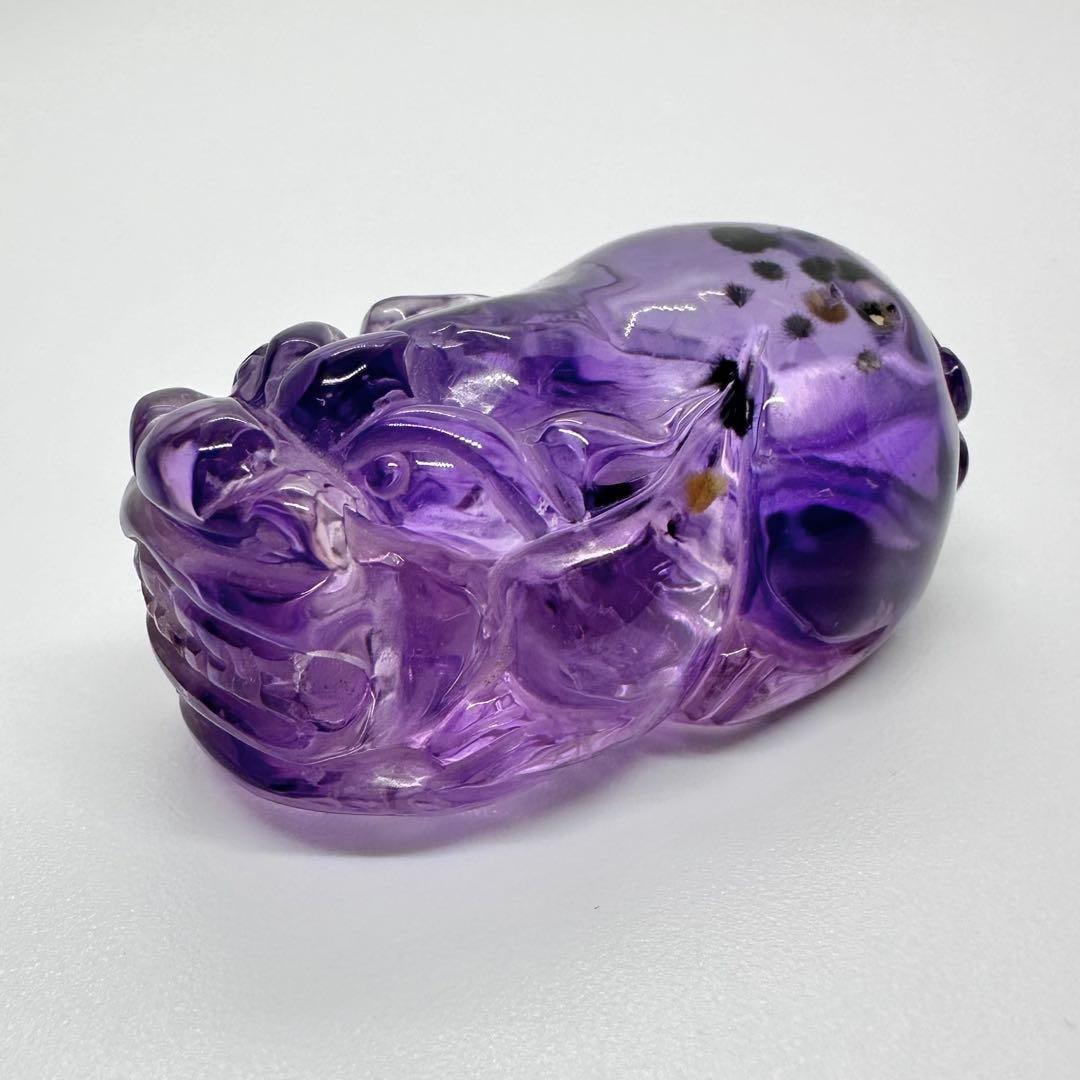 Amethyst Pixiu with Roman Stone: Amethyst Pixiu with Roman Stone Roman-style Amethyst Pixiu It features a through-hole. Dimensions are approximately 46 mm x 25 mm x 20 mm thick. There are some green substances and soil on the carved 