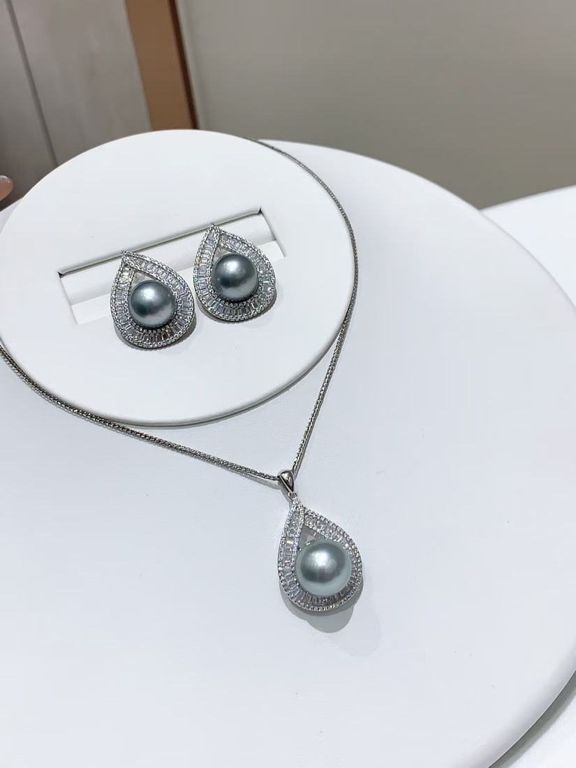Platinum Flawless Grey Pearl Set: This platinum grey pearl set exudes unparalleled elegance and sophistication. The flawless round pearls emit a captivating luster under light, with a design that enhances its luxurious appeal. Both