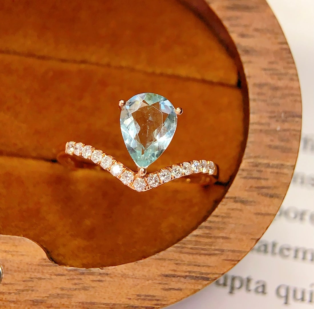 18K Gold Natural Aquamarine Ring: This ring is meticulously crafted in 18K gold, featuring a natural aquamarine that exudes a captivating brilliance. Surrounded by 15 diamonds, it adds a touch of luxury. The overall design is elegant