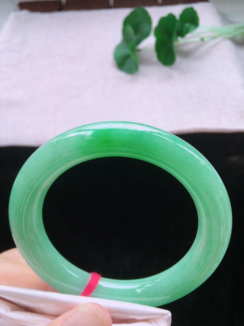 Icy Green Jadeite Bangle: This icy green jadeite bangle showcases a vibrant luster and a watery texture. Its rounded shape and perfect craftsmanship make it suitable for various occasions. (Size 57.1/11/11.2) Freight: 1.Intern