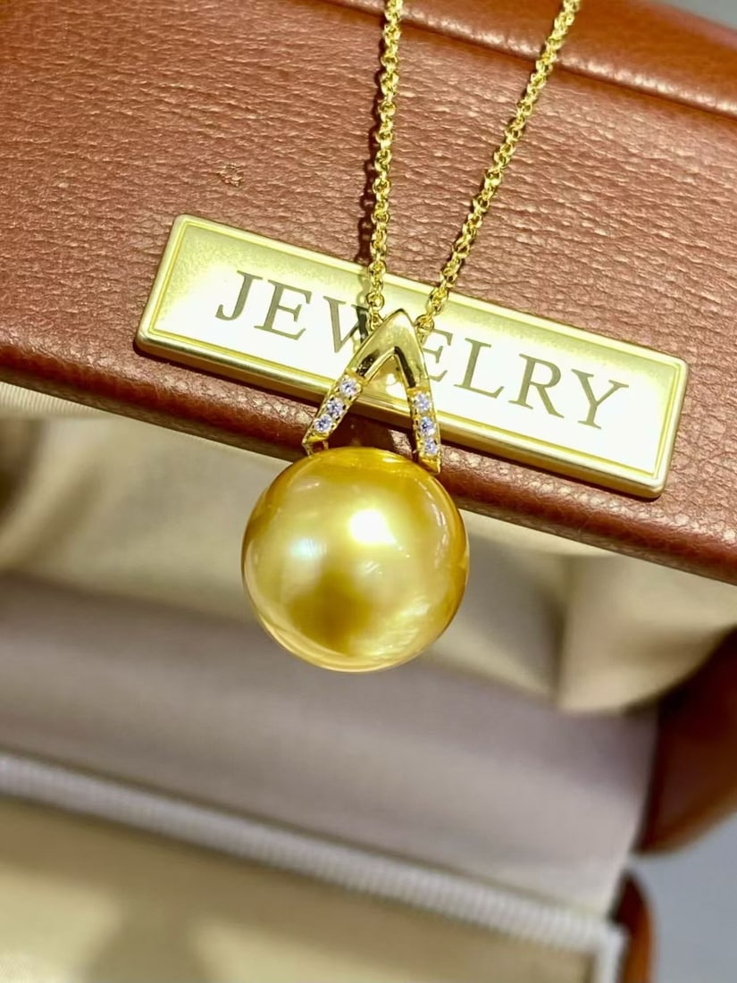Natural Golden Pearl Pendant: This pendant features a natural golden pearl with an intense tea-gold hue. The pearl has slight blemishes but boasts extraordinary luster, with top-tier color and sheen. It is elegantly complemented b