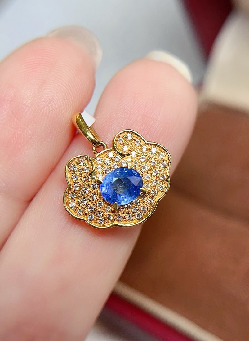 18K Gold Sapphire Pendant: This pendant is meticulously crafted in 18K gold, set with a brilliant sapphire that exudes a captivating glow. The design inspiration of cornflower combined with the shape of a Ruyi lock presents a
