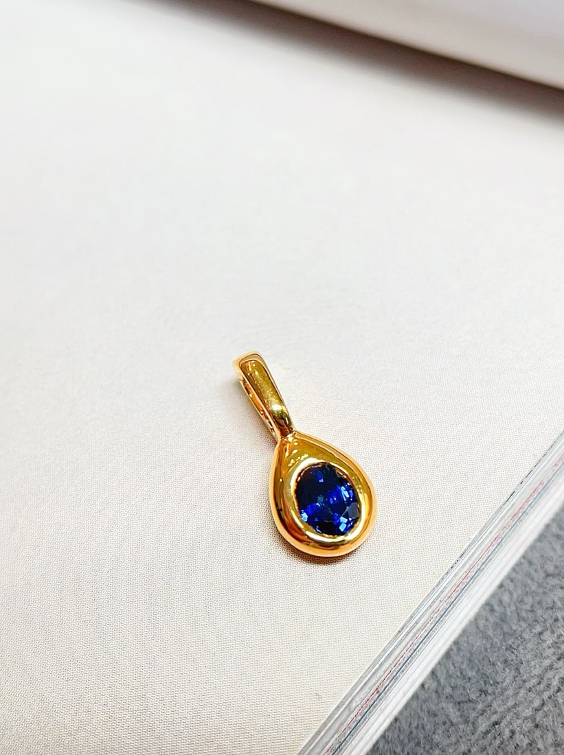 18K Gold Royal Blue Sapphire Pendant: This pendant is crafted in 18K gold, set with a royal blue sapphire, showcasing an elegant minimalist style. The sapphire's deep hue is captivating. Suitable for various occasions, it reflects