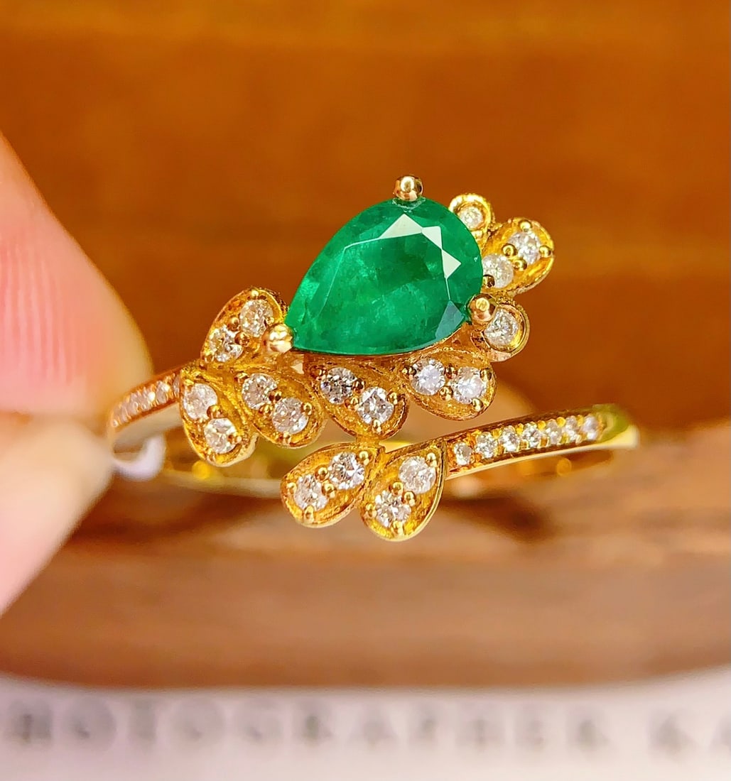 18K Gold Natural Emerald Ring: This ring is meticulously crafted in 18K gold, featuring a natural emerald that exudes an aura of elegance and nobility. The main stone is a 0.8-carat emerald, surrounded by 31 sparkling diamonds. The