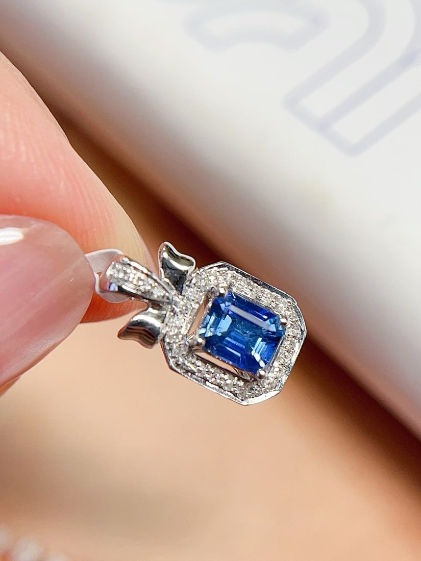 18K Gold Sapphire Pendant: This pendant is meticulously crafted in 18K gold, featuring a sapphire that exudes cornflower-like elegance. The emerald cut design enhances its brilliance, complemented by 28 diamonds for added luxur