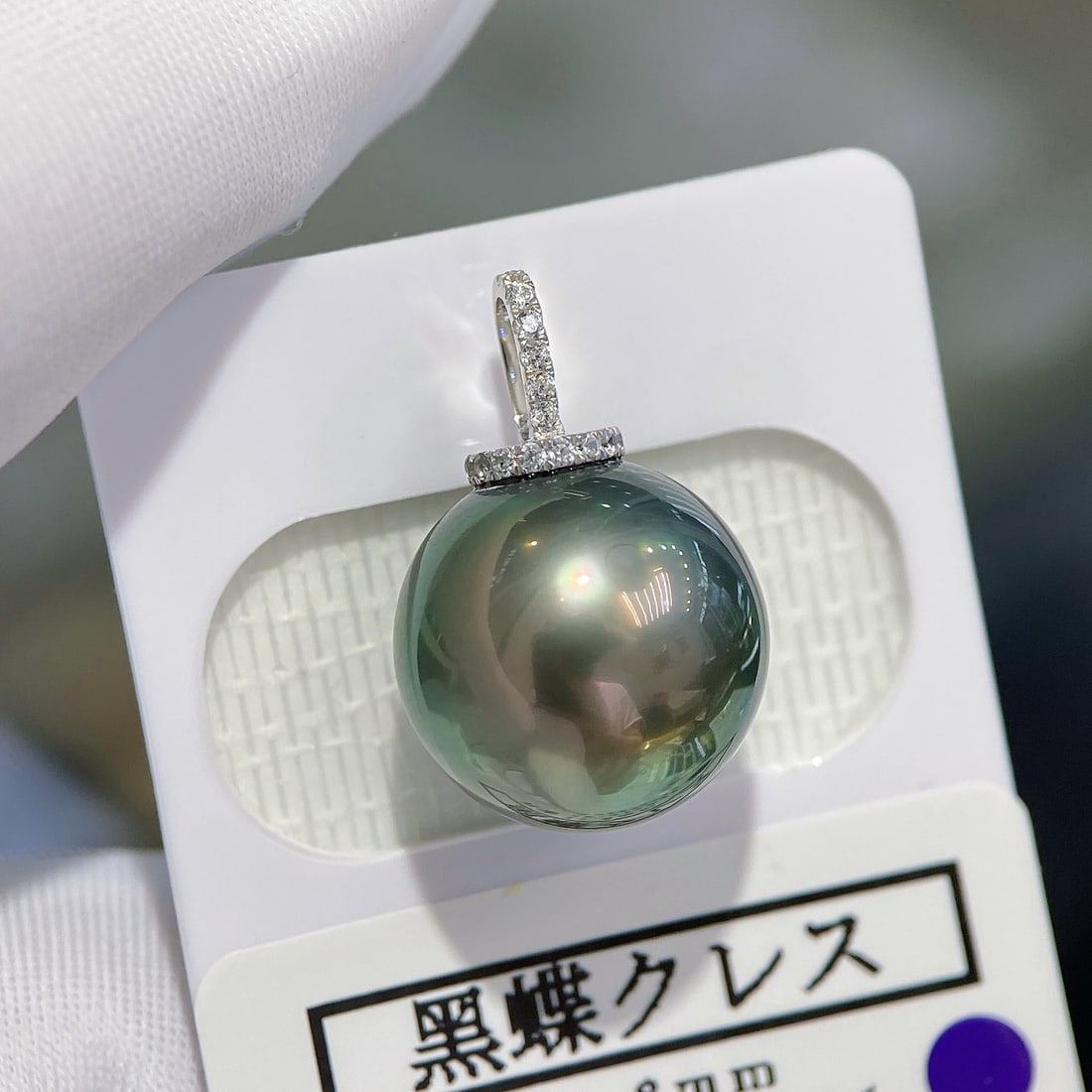 18K Gold Tahitian Pearl Pendant: This Tahitian pearl is renowned for its 12.8mm perfect round shape and minimal blemishes, showcasing a smooth texture akin to baby skin. Paired with an 18K white gold clasp, the design is elegant and 