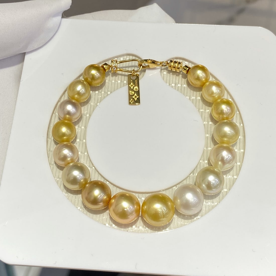 White South Sea Pearl Bracelet: This bracelet is made of white South Sea pearls, showcasing a high quality with very slight blemishes. The natural luster of the pearls combined with gold beads adds a touch of elegance. Each pearl is